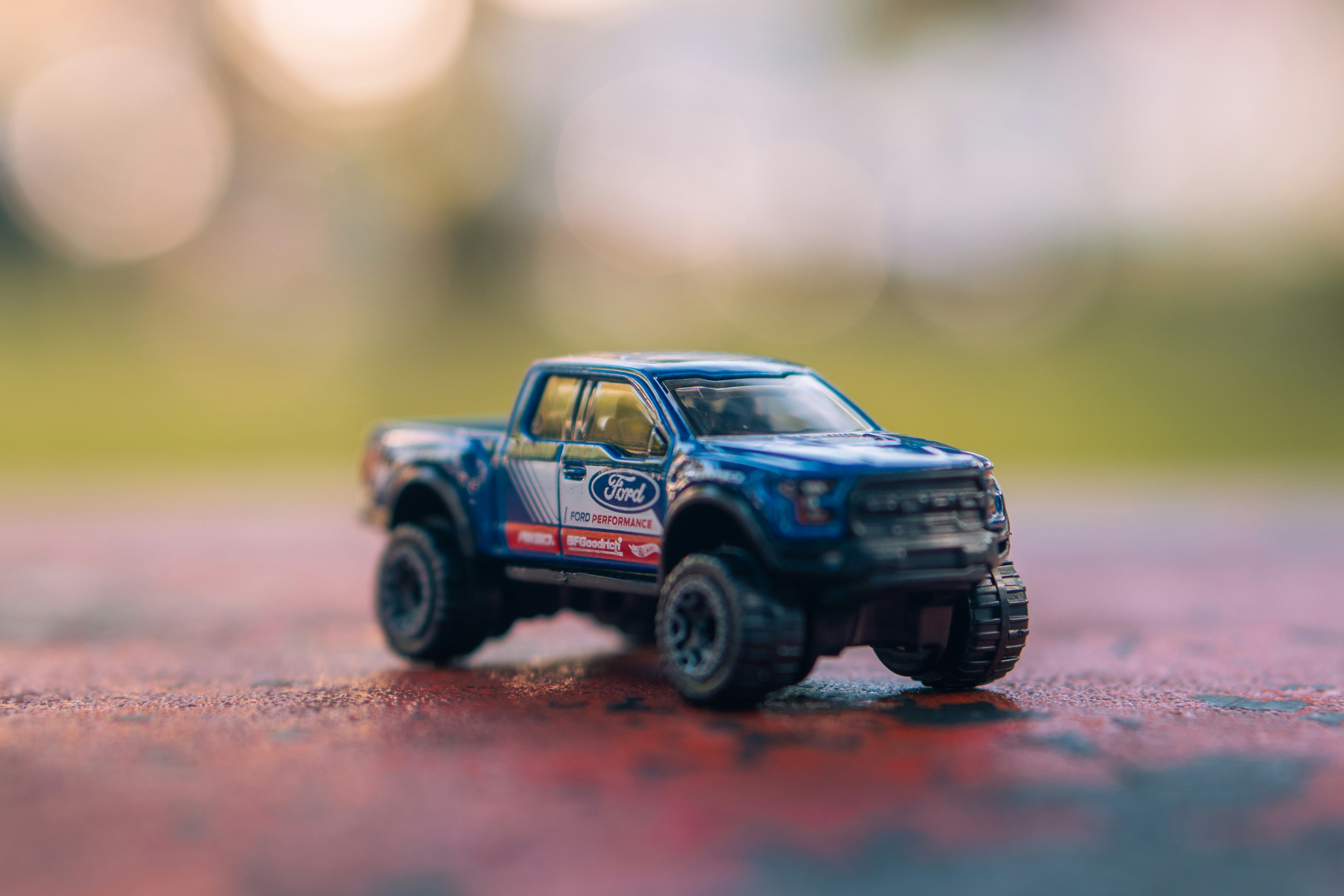 A blue toy truck sits on a reddish surface.