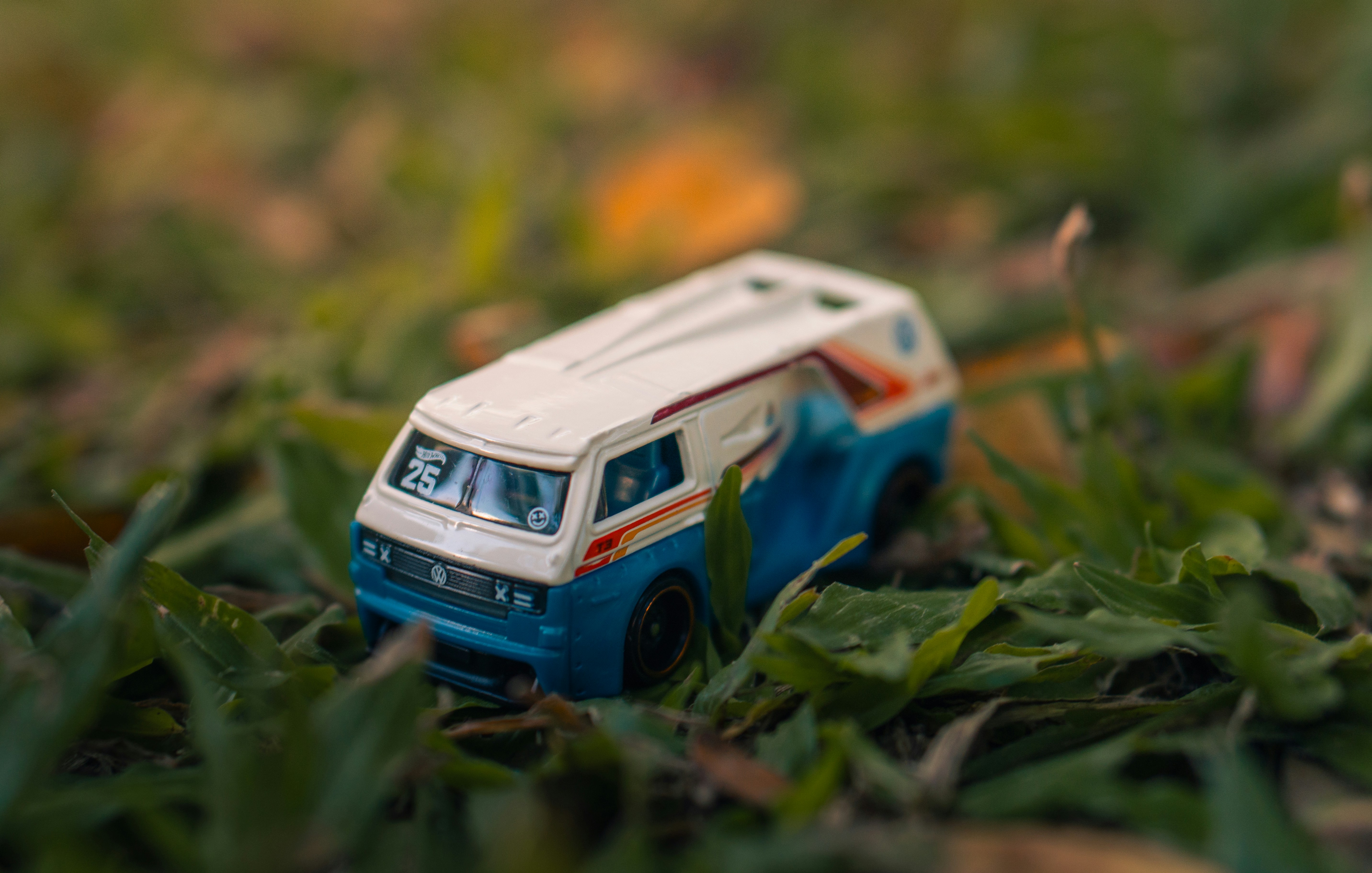 Small white and blue toy van resting on green grass.