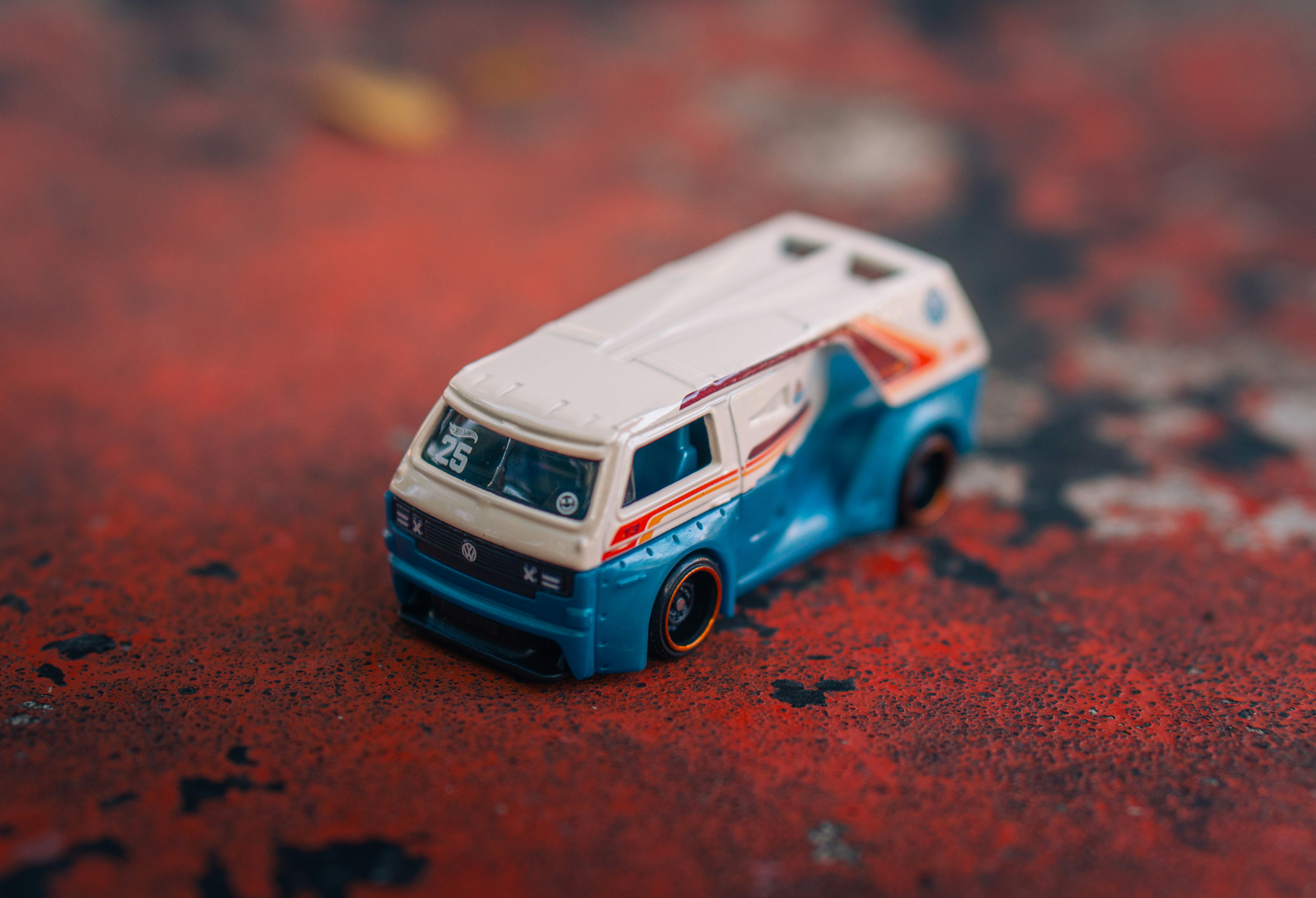 A blue and white toy van on a red surface.