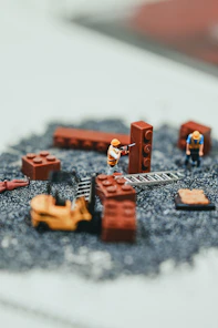 Miniature construction workers building with brown lego bricks