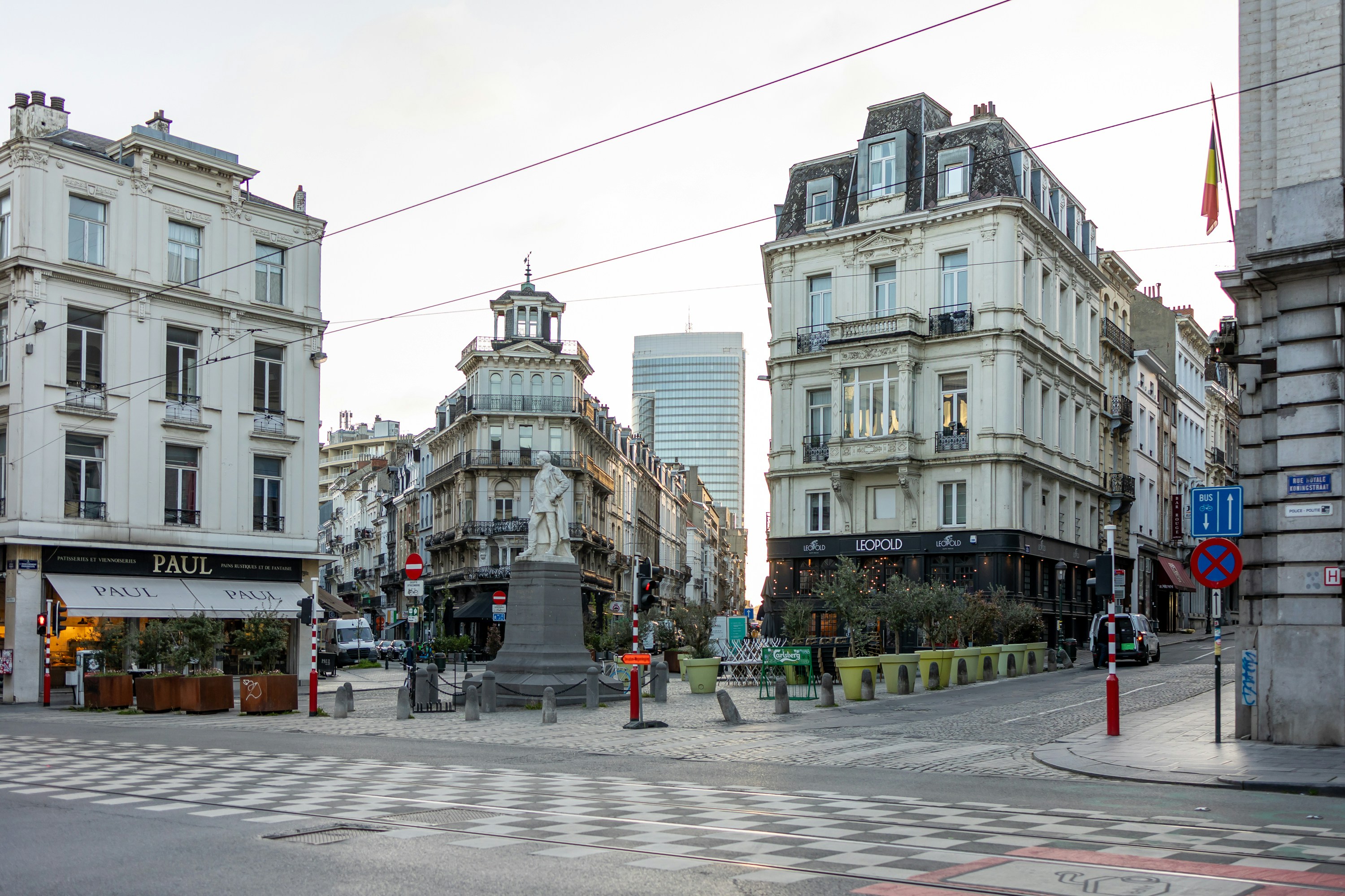 European city intersection with historic buildings and a central statue.