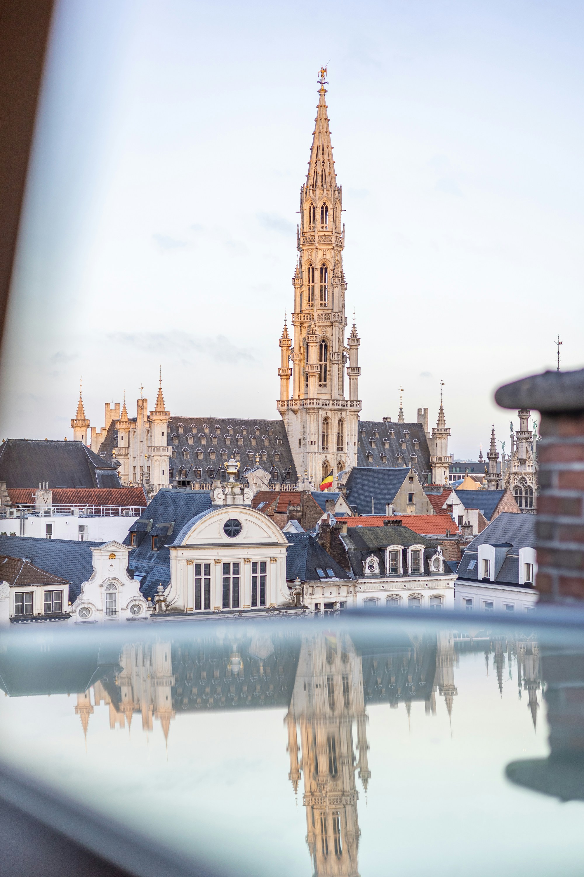 Historic city hall spire reflected in a window.