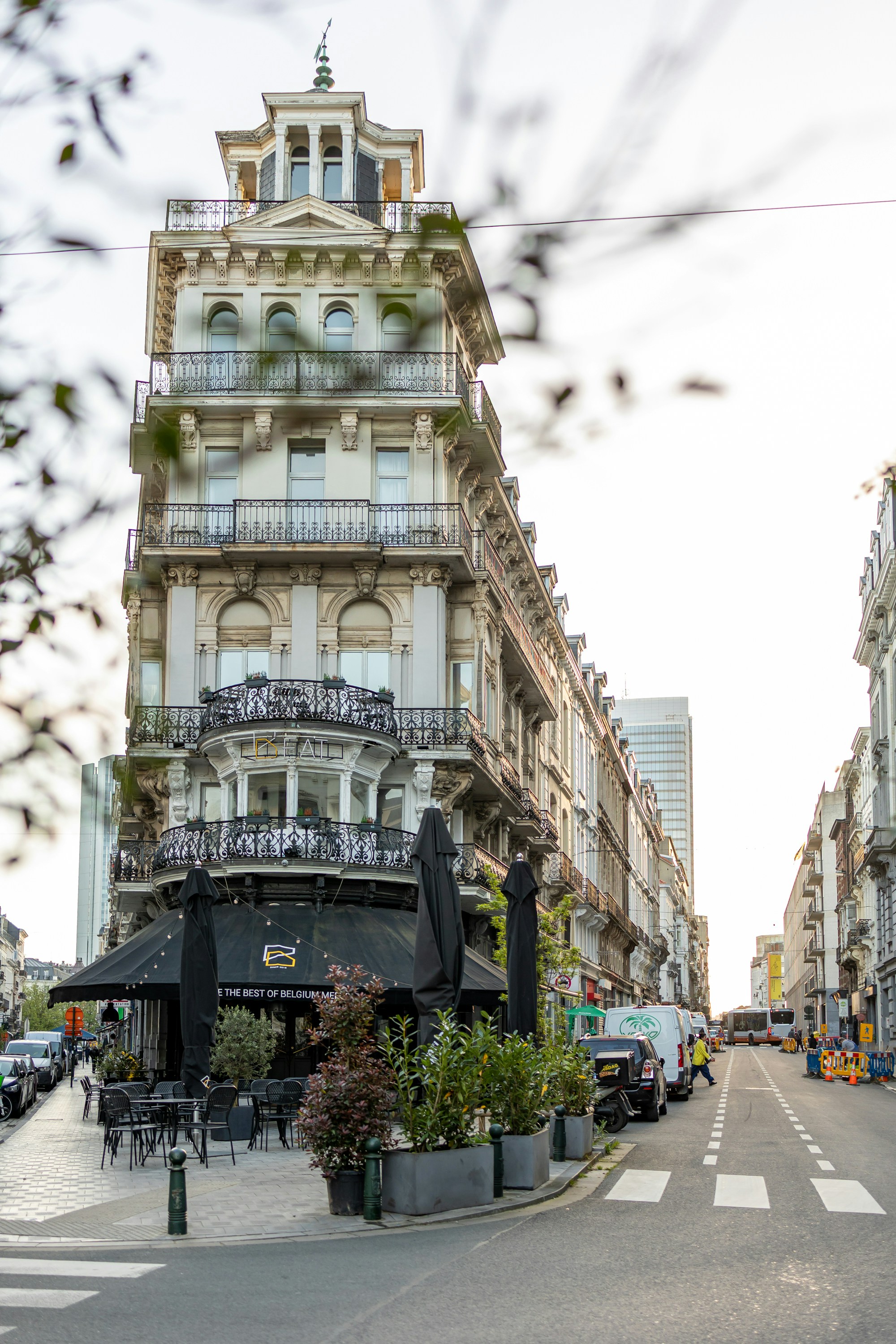 Grand european building with a street cafe and outdoor seating.