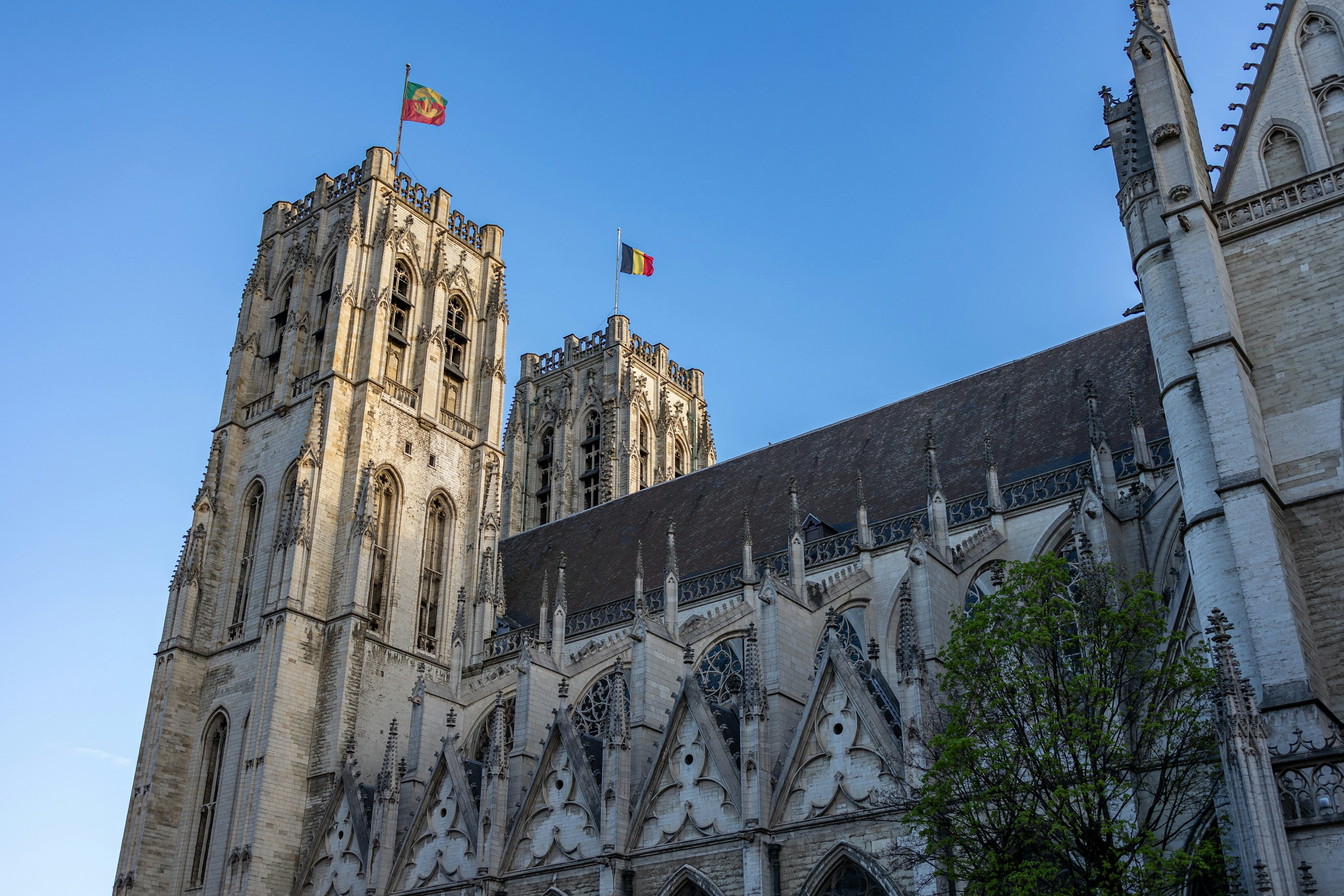 Majestic cathedral towers with flags under a clear blue sky.