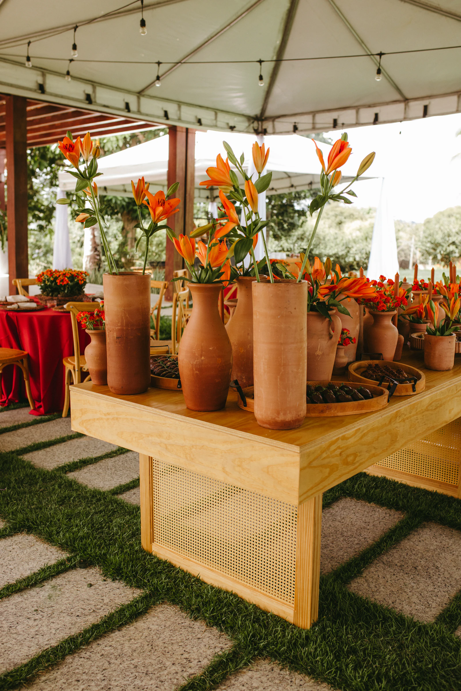 Longue table de mariage dressée avec des vases en terre cuite et du feuillage vert sauge