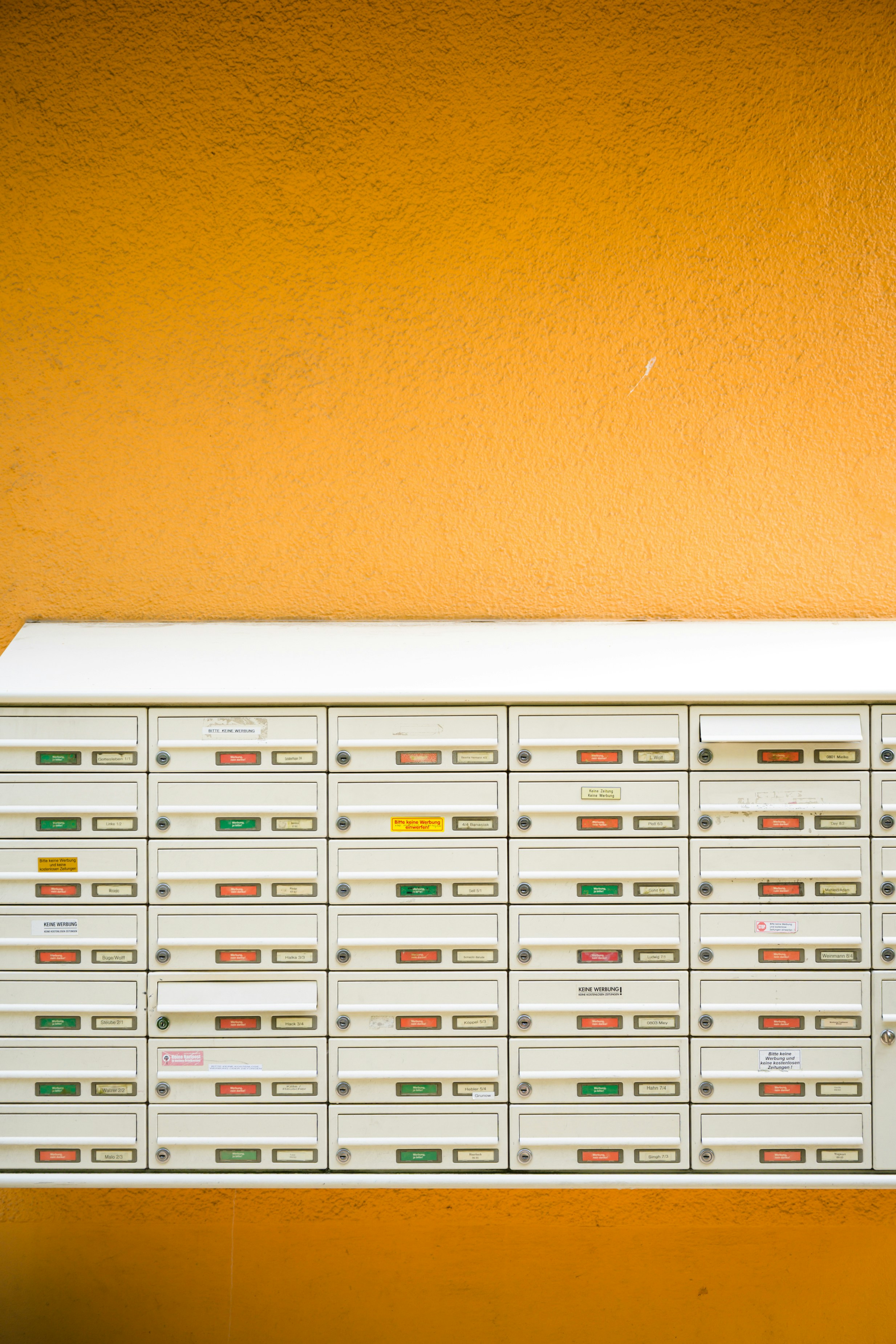Una parete di cassette postali su uno sfondo arancione vibrante.