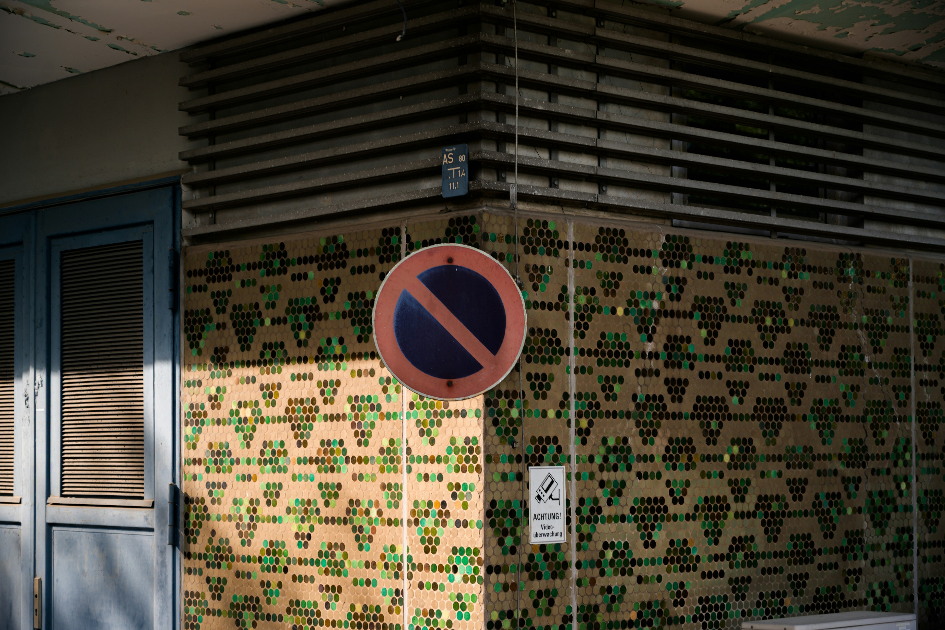A no parking sign on a patterned tiled building wall