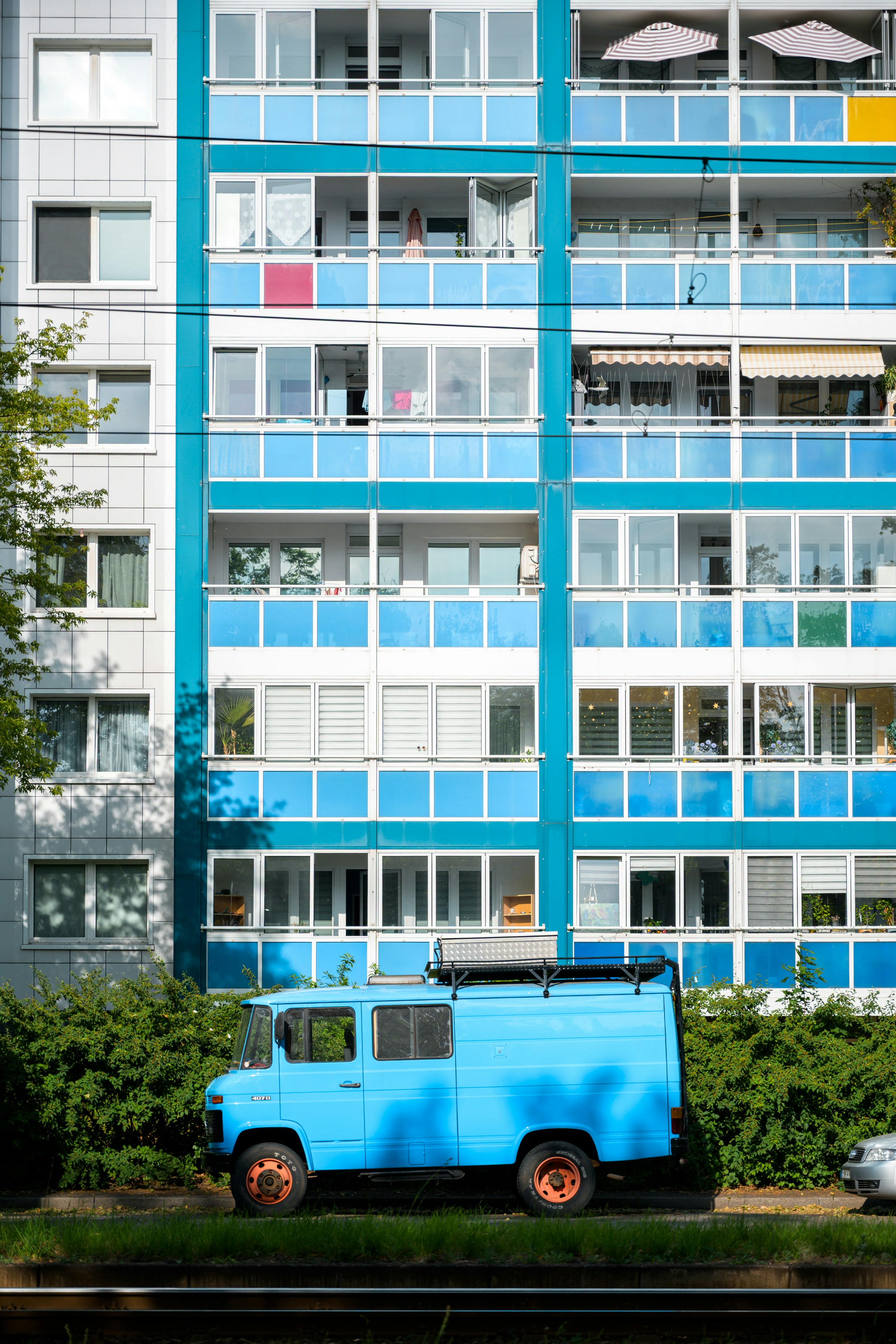 Bright blue van parked against a modern apartment building.