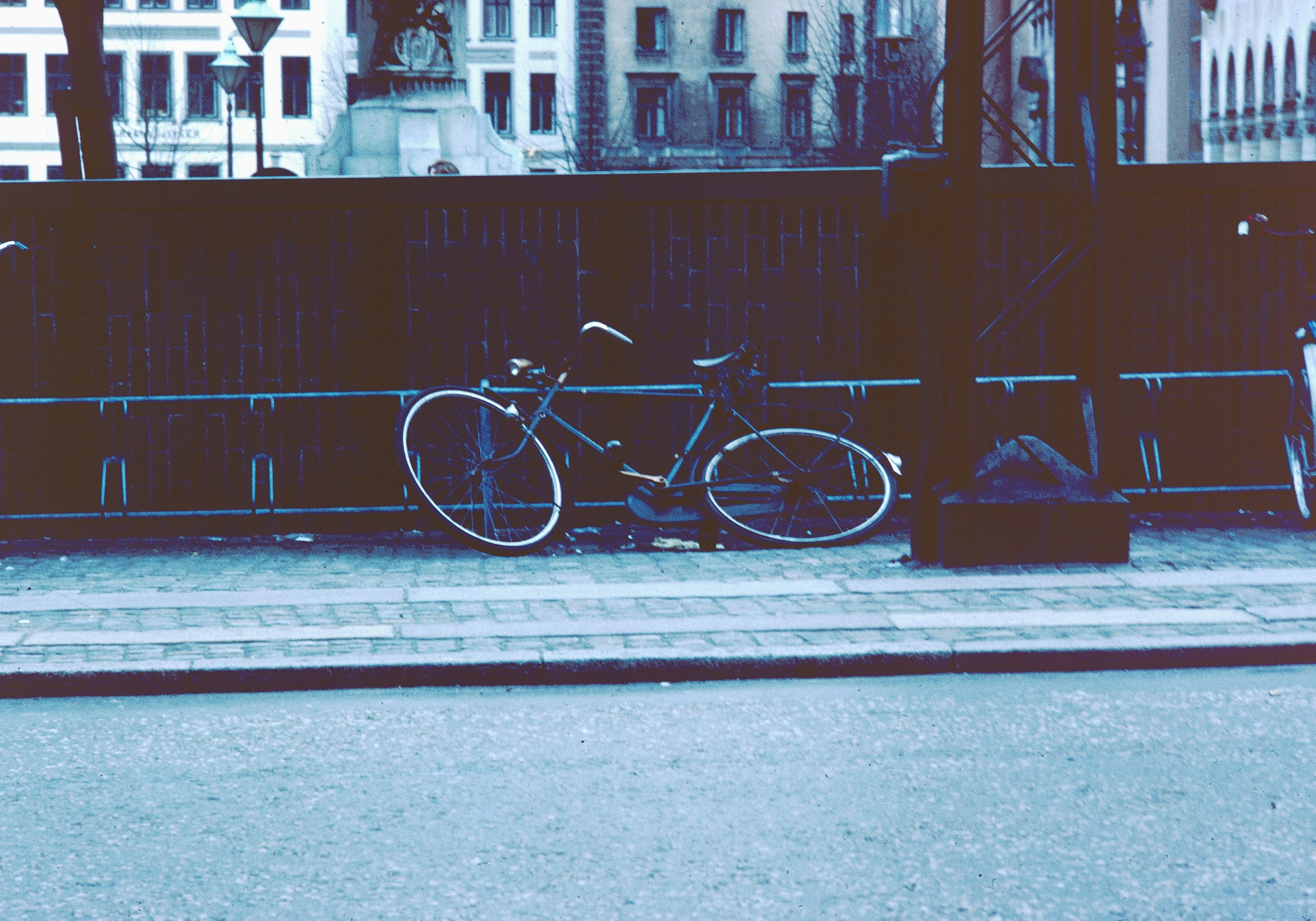 Bicycle leaning against a fence on a city street