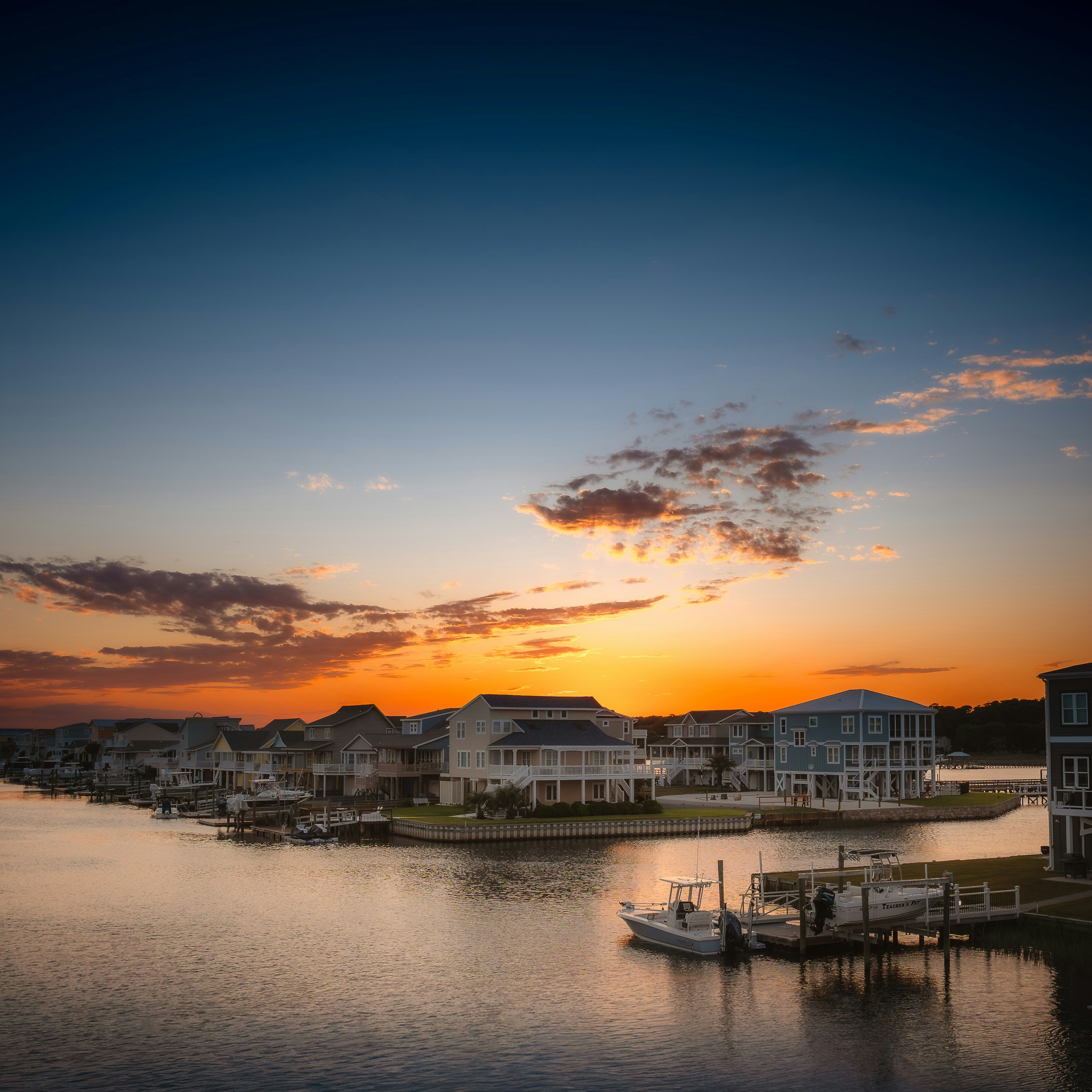 Sunset over a waterfront community with houses and boats.