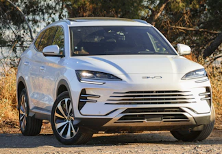A white electric suv parked outdoors on a dirt road.