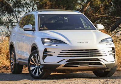 A white electric suv parked outdoors on a dirt road.