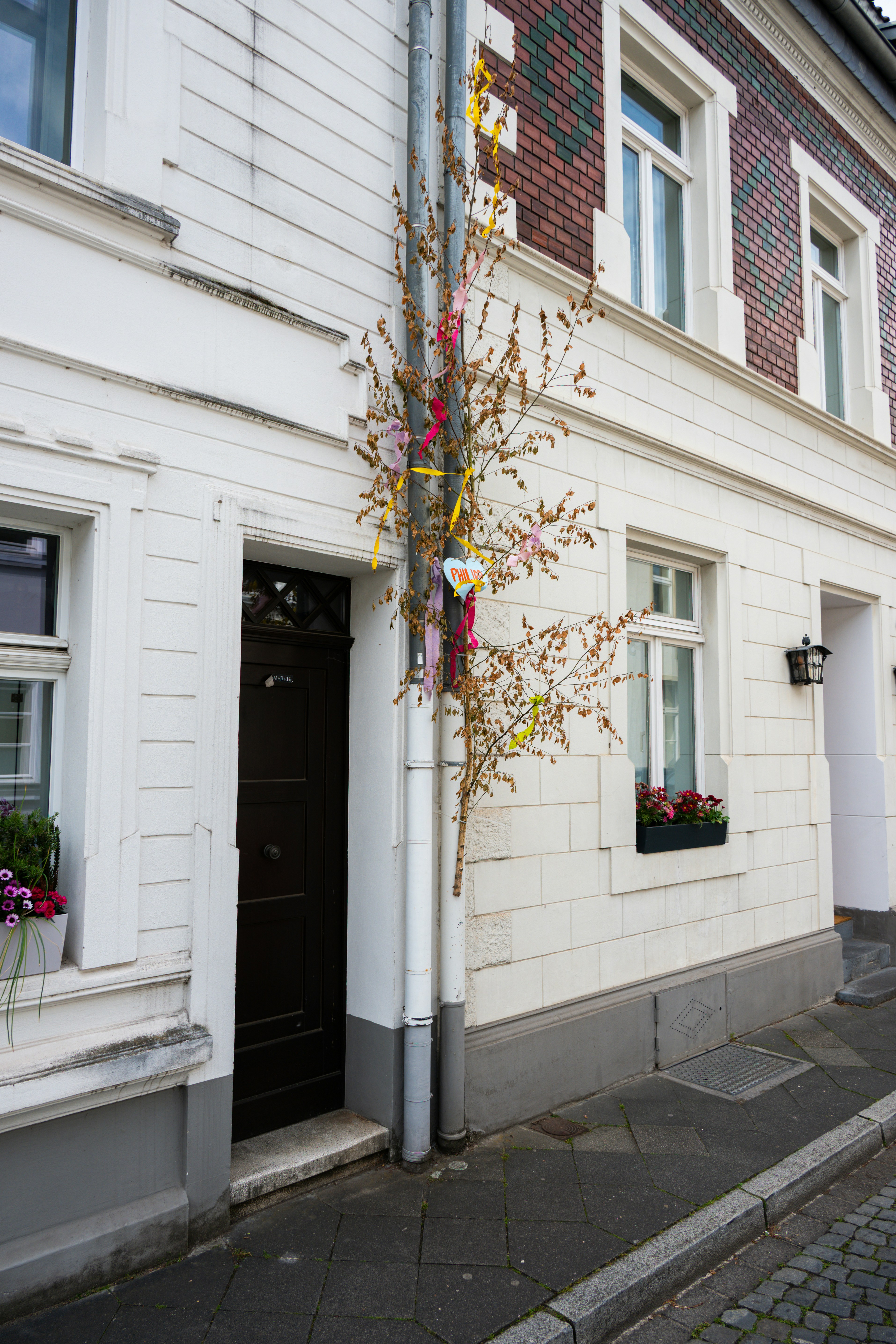 Easter tree decoration on a white building's downspout.