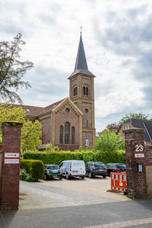 Old brick church with a steeple overlooks a parking lot