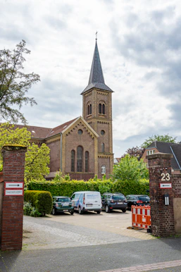 Old brick church with a steeple overlooks a parking lot