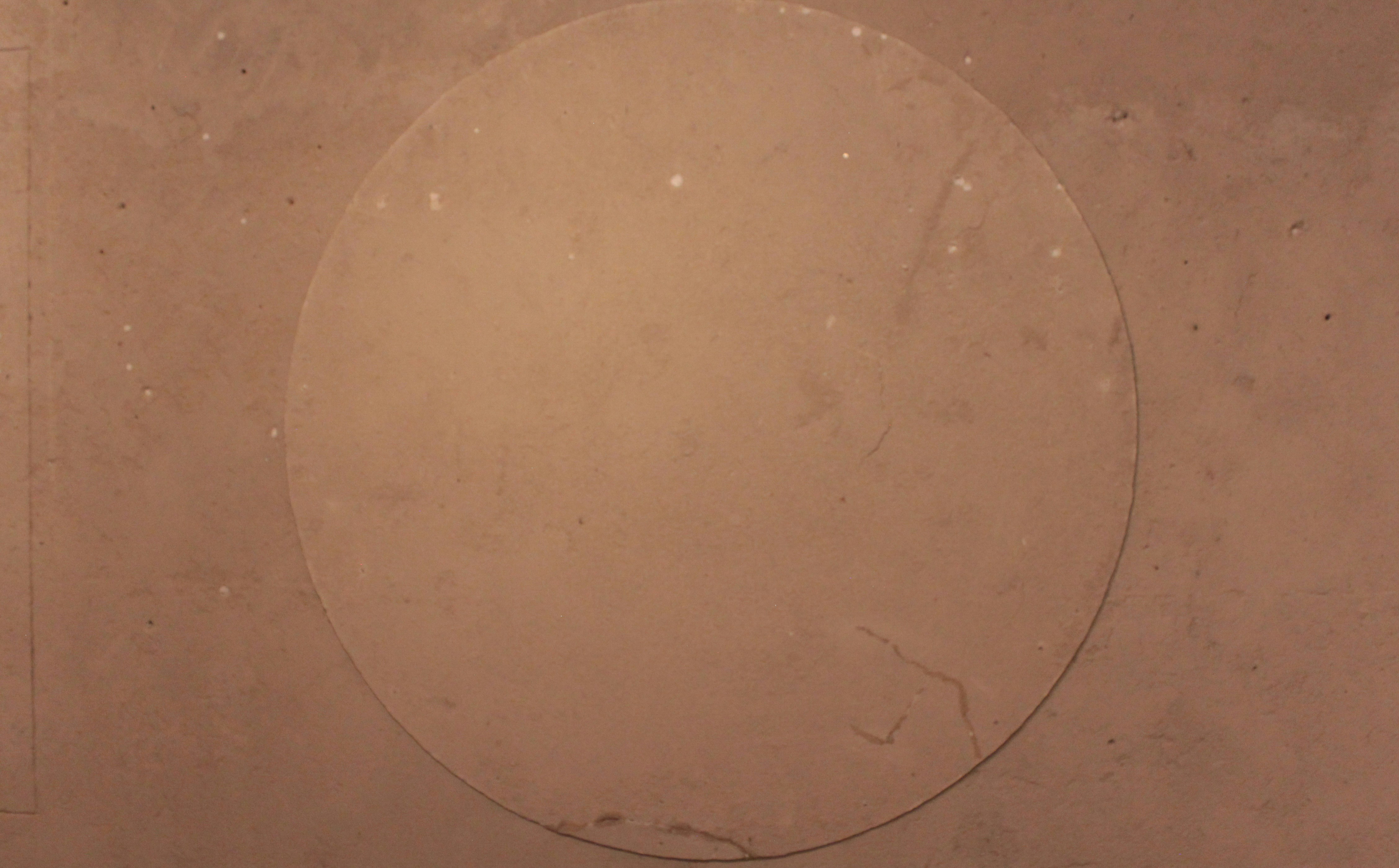Une forme circulaire marron clair sur un fond texturé.
