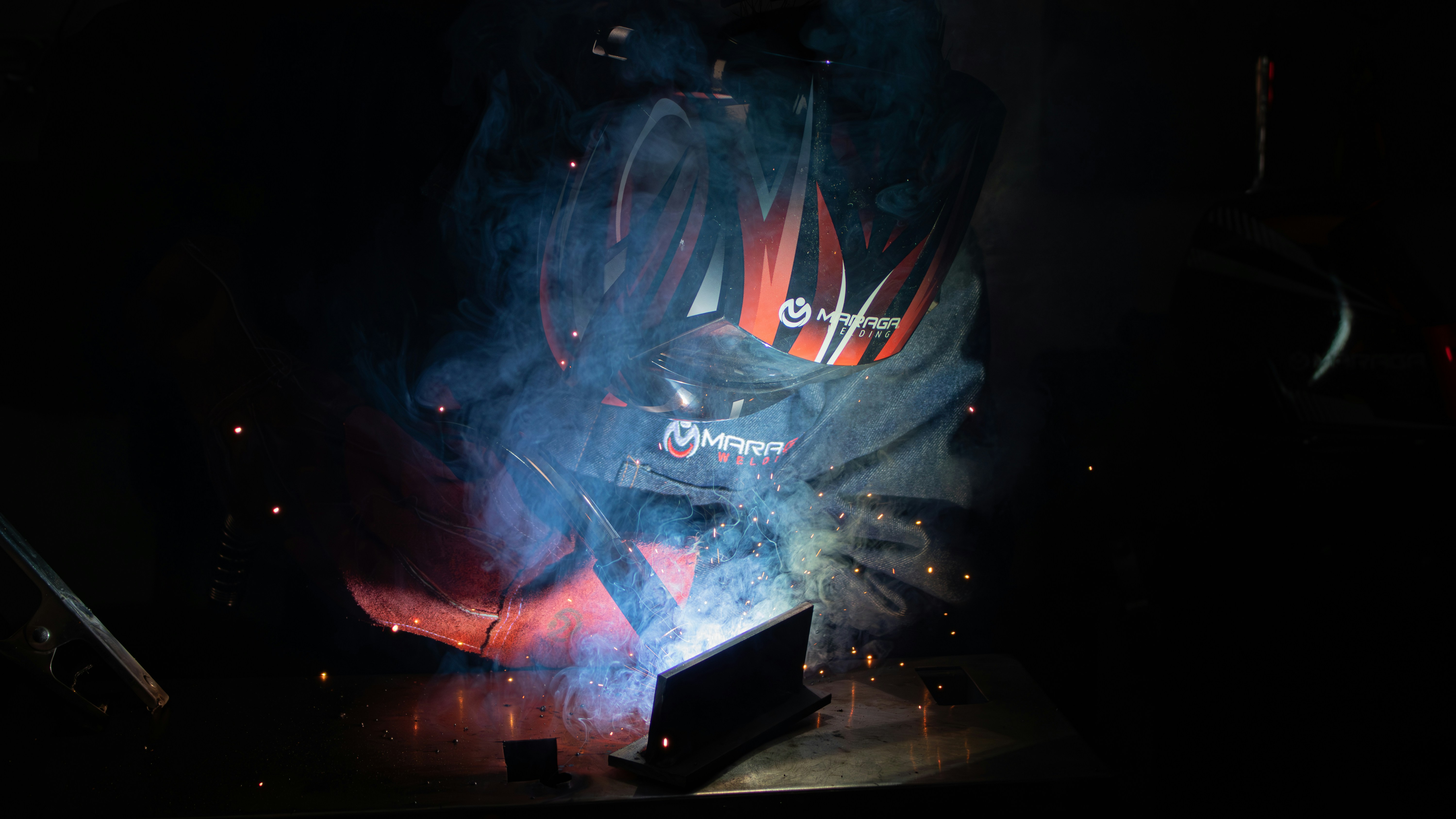 A person welding metal, creating bright sparks and smoke.