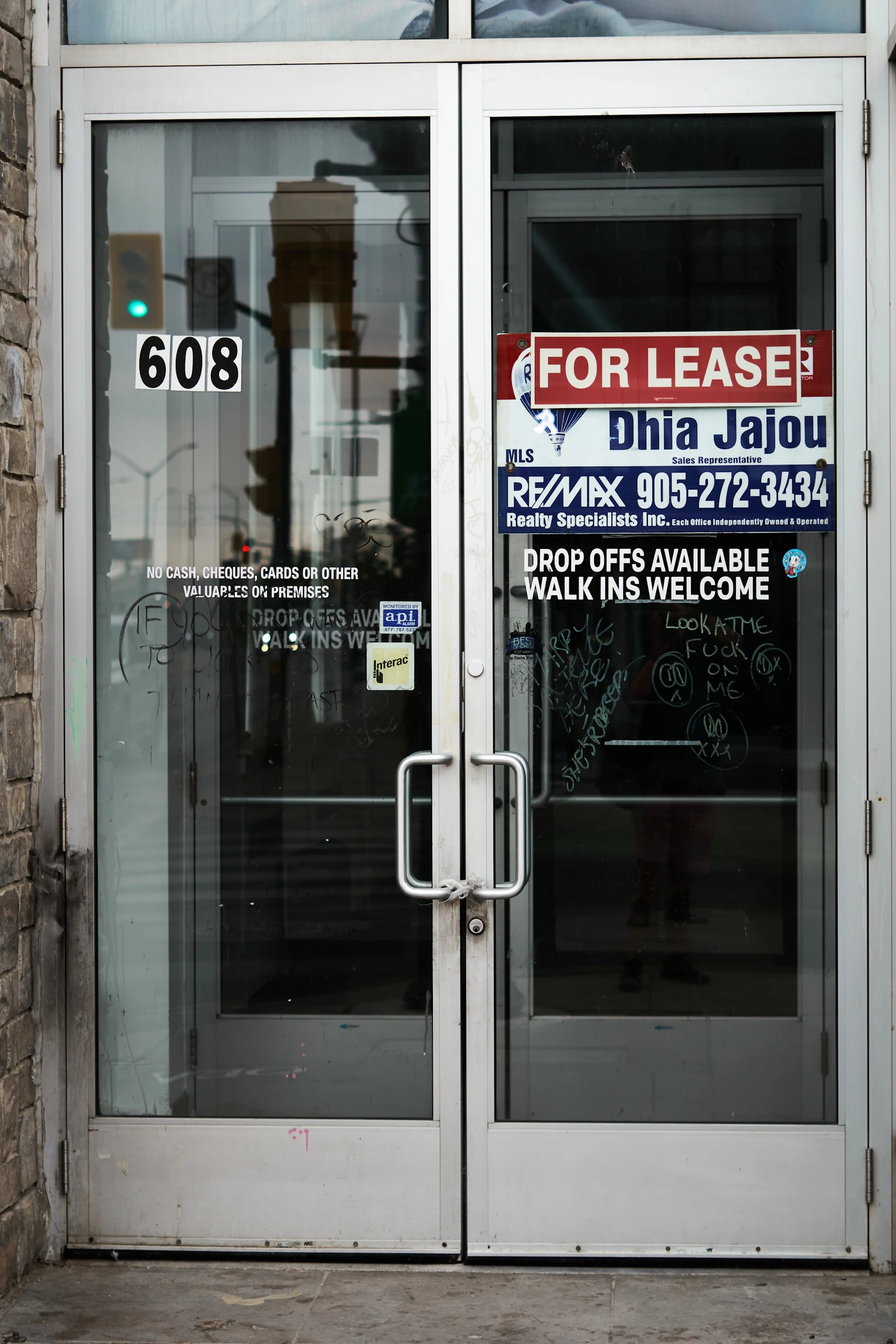 A for lease sign taped to the glass doors of an empty commercial unit