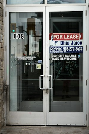 A for lease sign on the glass double doors of an empty commercial storefront, like the vacant spaces tenants describe at New Orleans Square