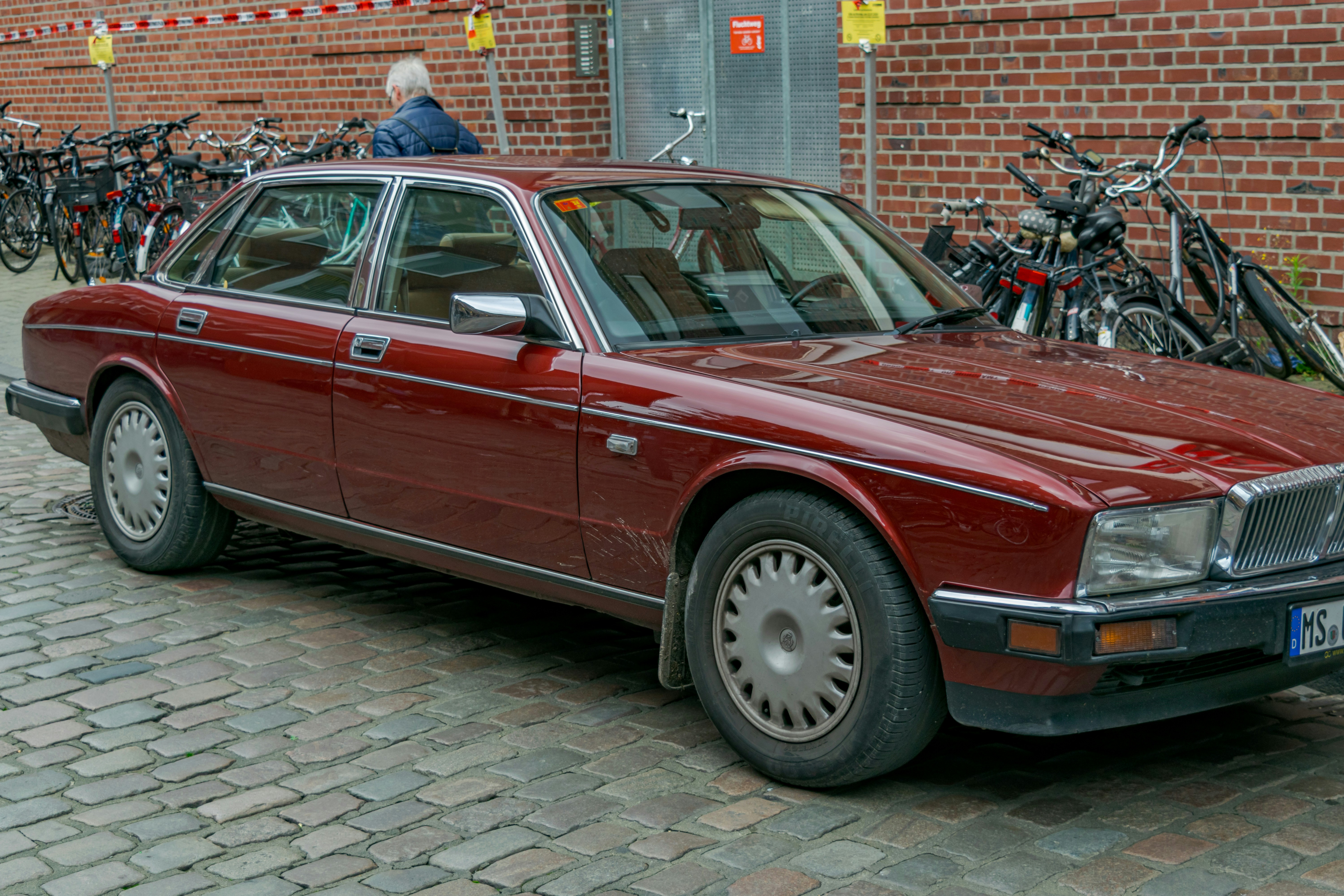 A classic red sedan parked on a cobblestone street.
