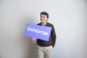Smiling man holds a purple "expertise" sign.