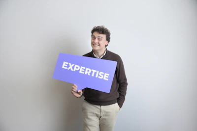 Smiling man holds a purple "expertise" sign.