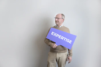 Man holding an "expertise" sign looking left.