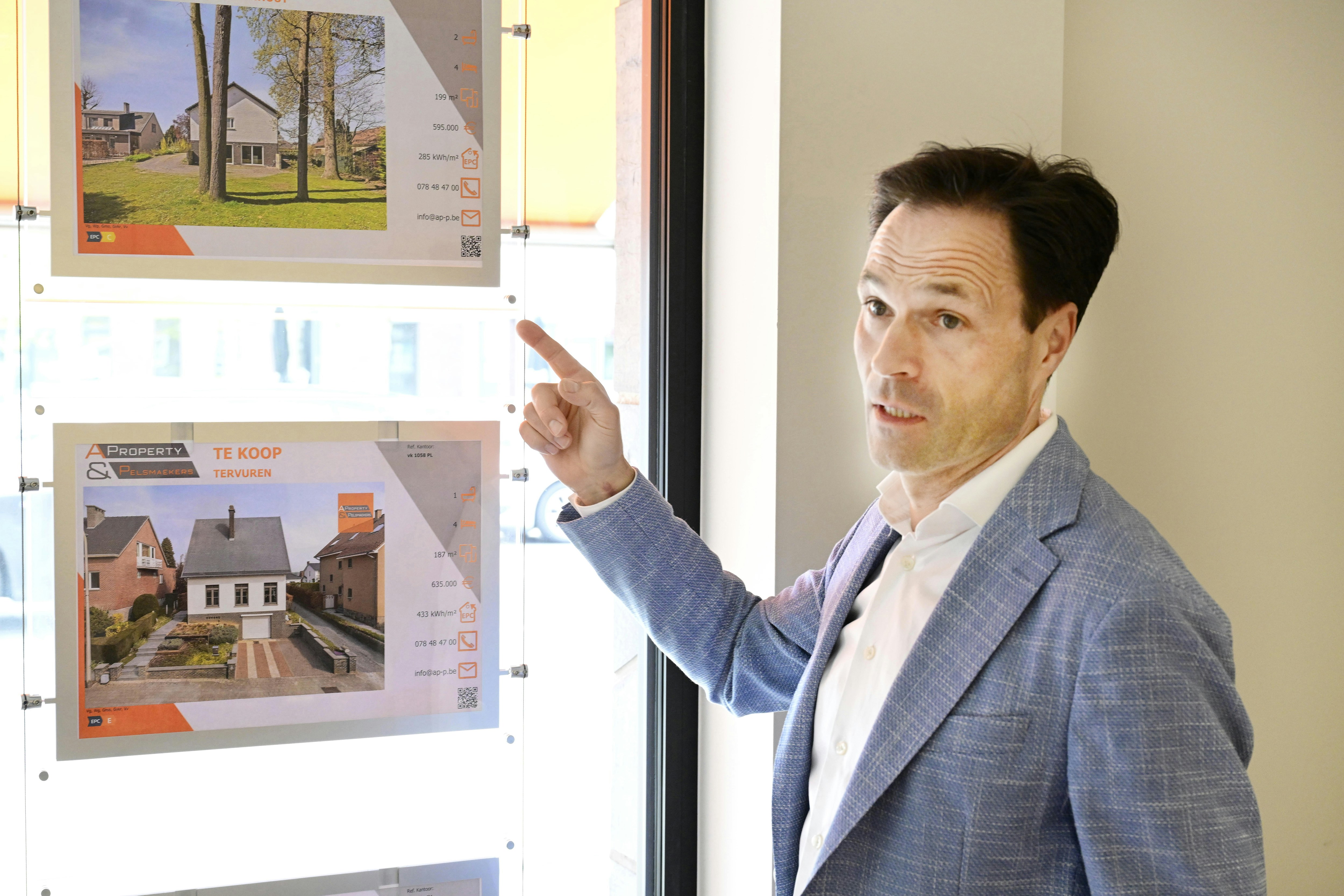 Mann zeigt auf Immobilienangebote in einem Fenster.