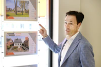 Man pointing at property listings displayed in a window.