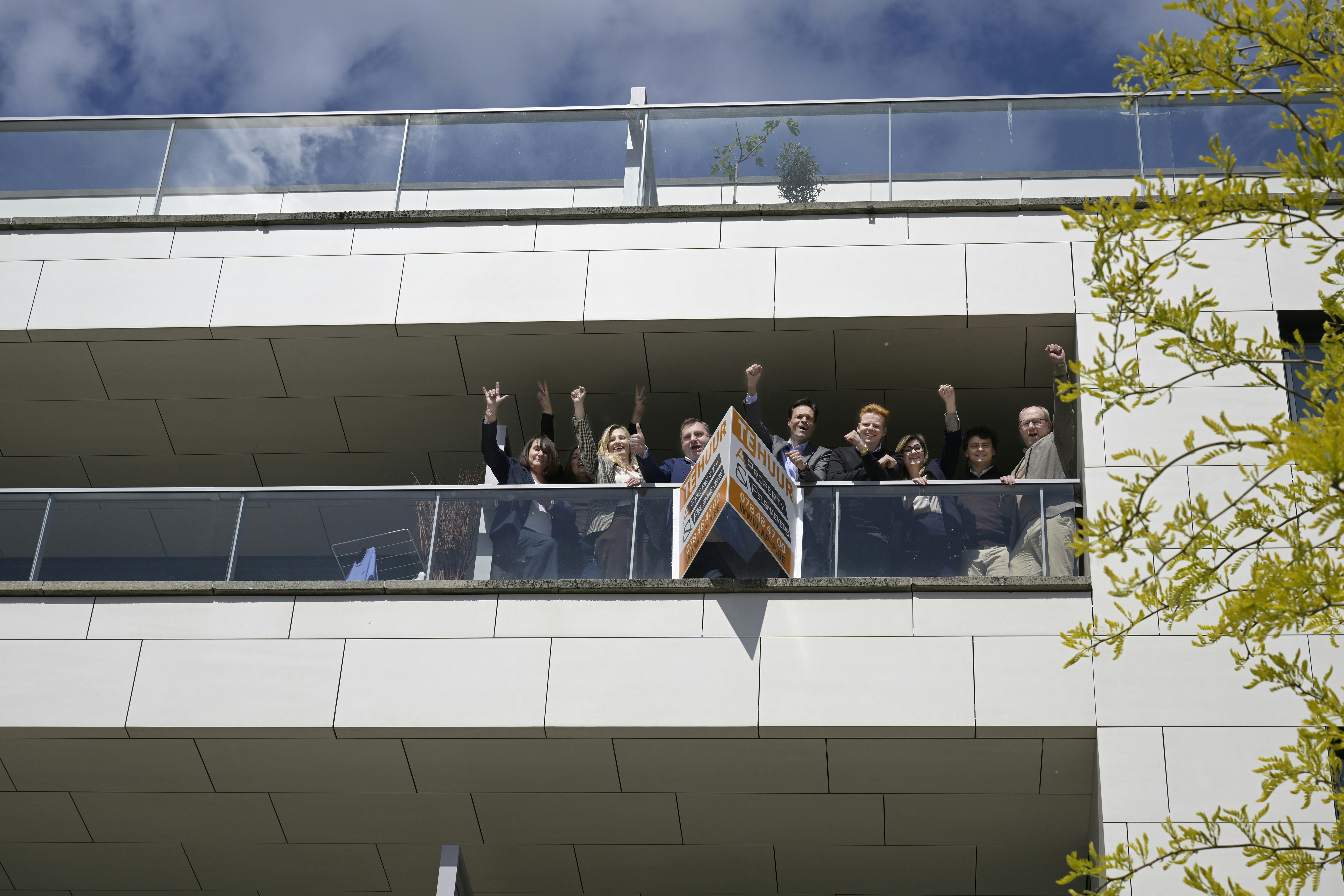 People raise fists in celebration on a building balcony
