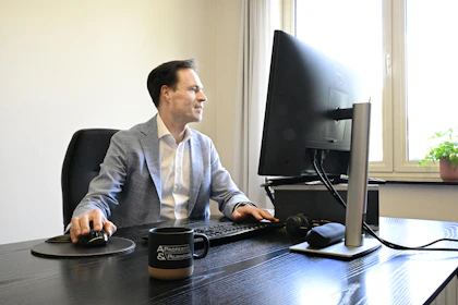 A man in a suit works at a computer desk
