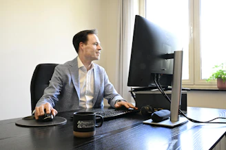 A man in a suit works at a computer desk