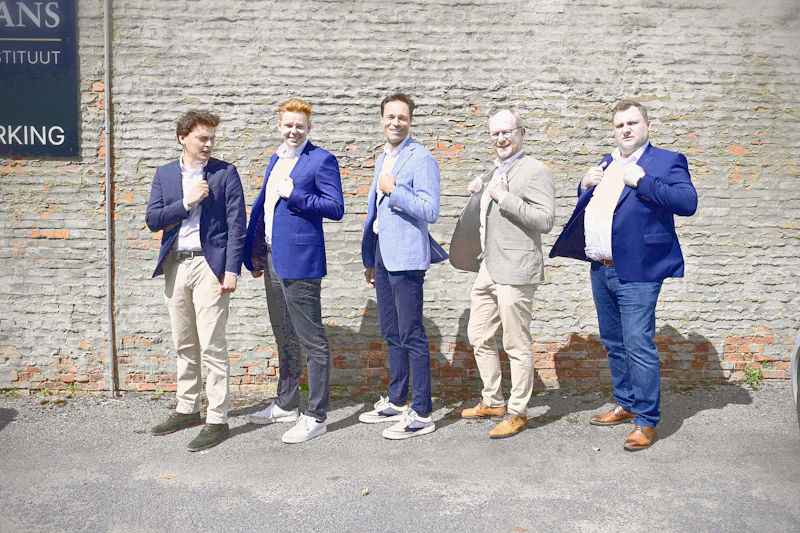 Five men in blazers standing by a brick wall