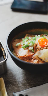A bowl of ramen with pork, egg, and green onions