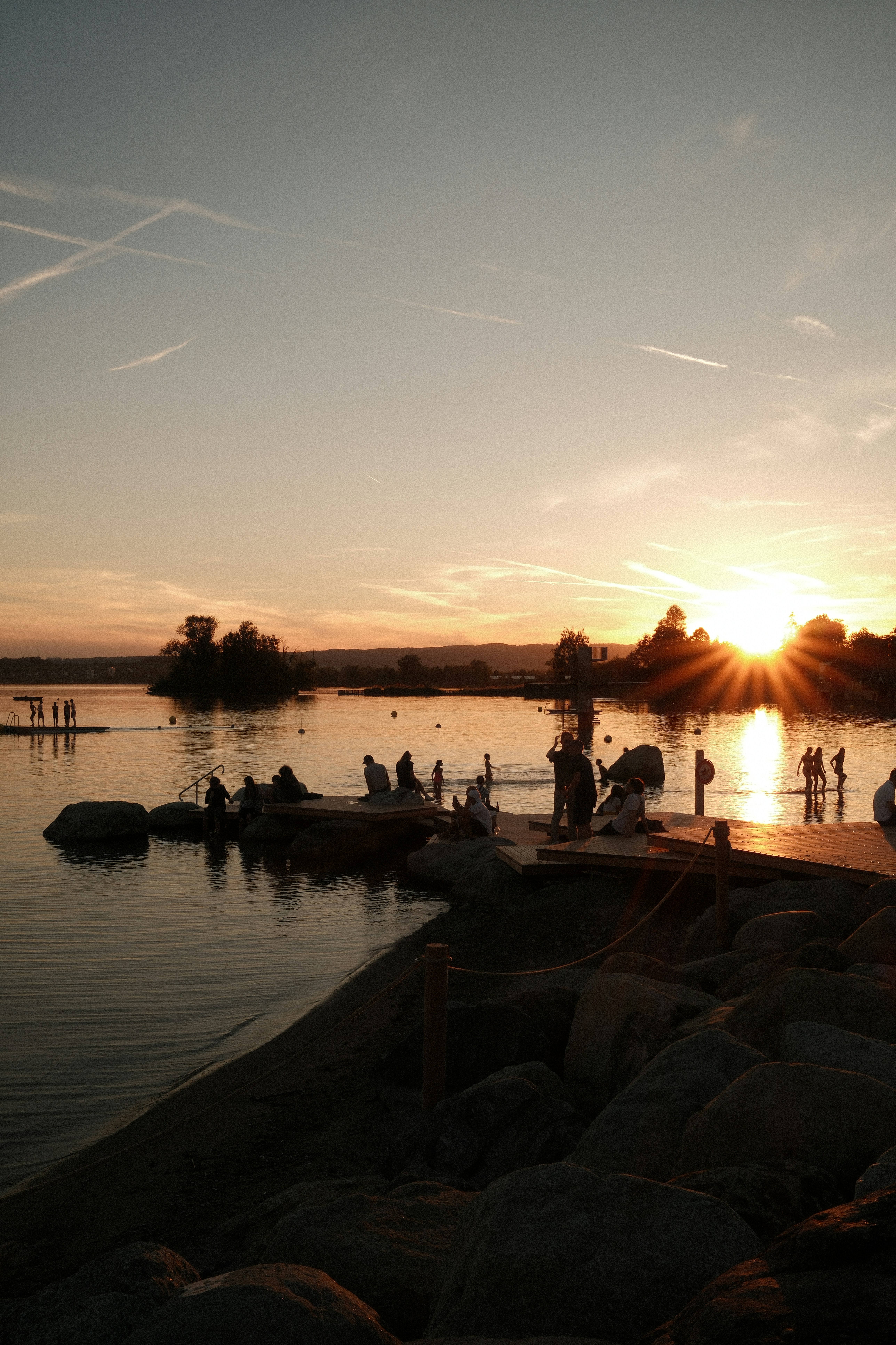 Golden sunset over water with silhouetted people on shore.