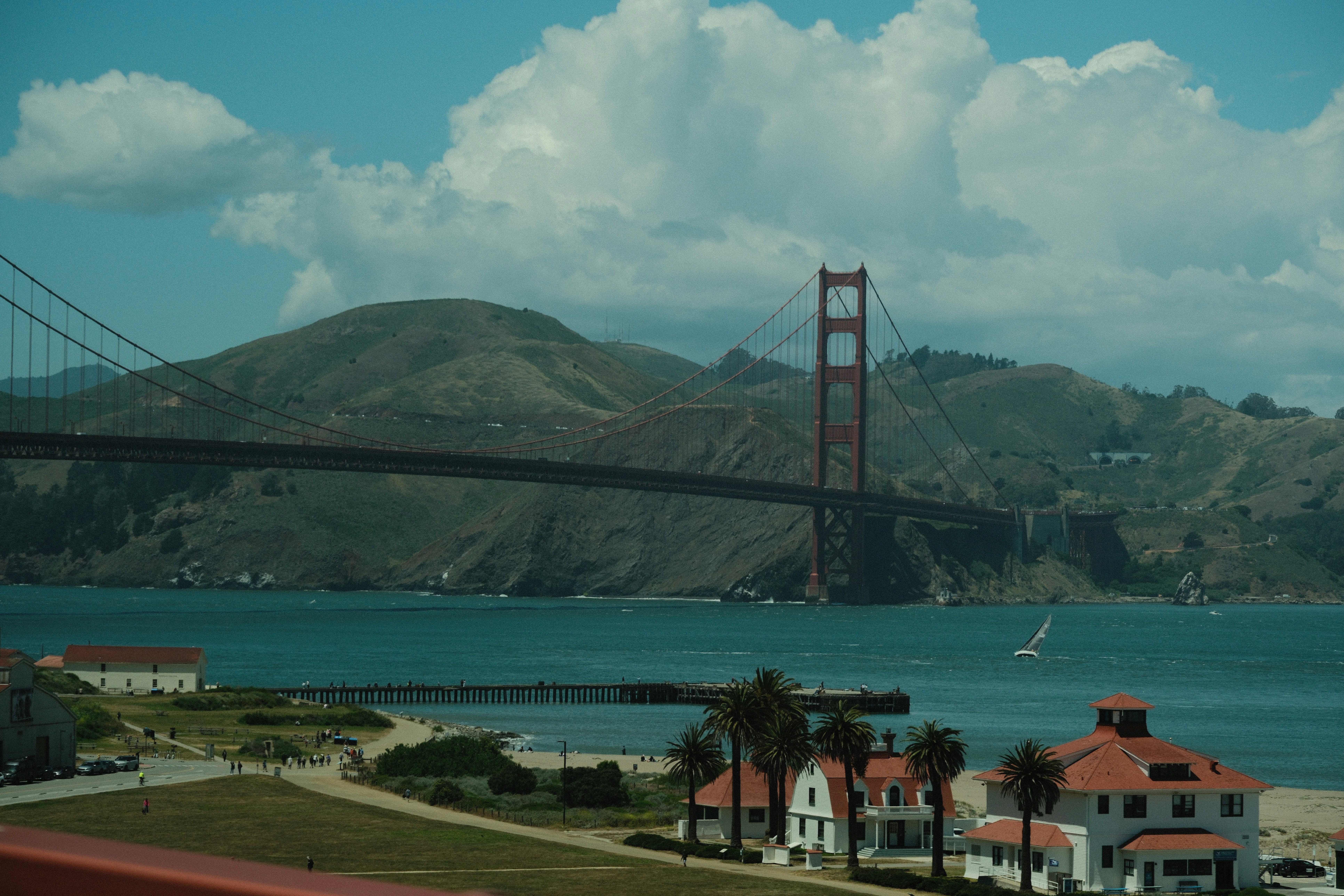 Golden gate bridge spans a bay with buildings and hills.