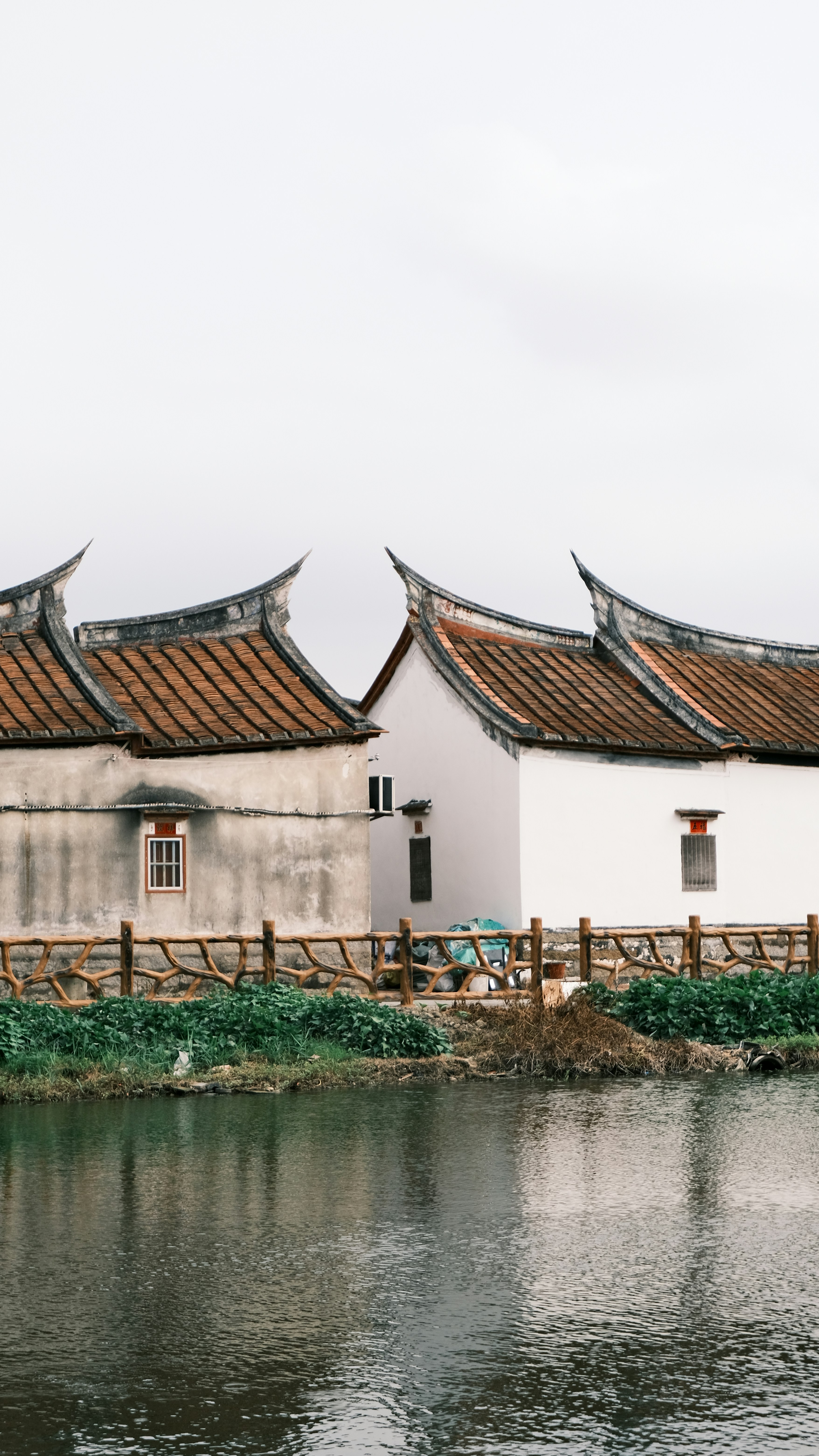 Traditional chinese houses with curved roofs by a calm river.