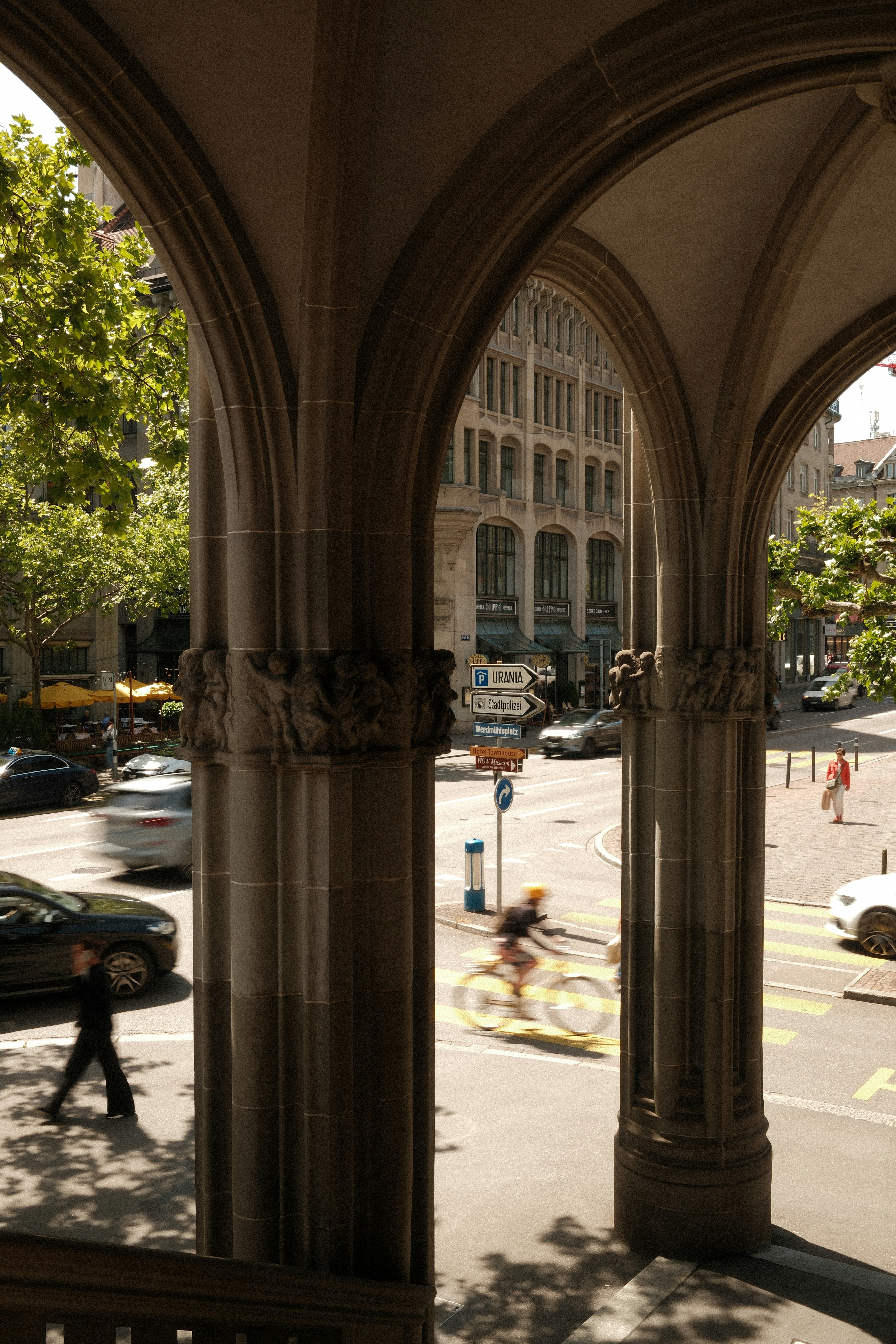 Ornate stone arches frame a busy city street scene.