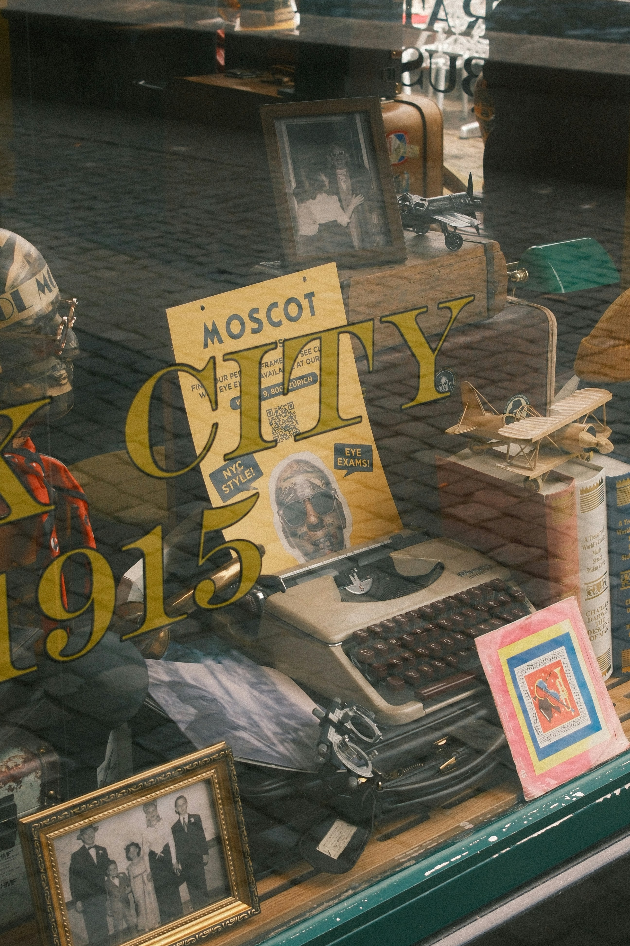 Vintage display with old typewriter and framed photos in window.