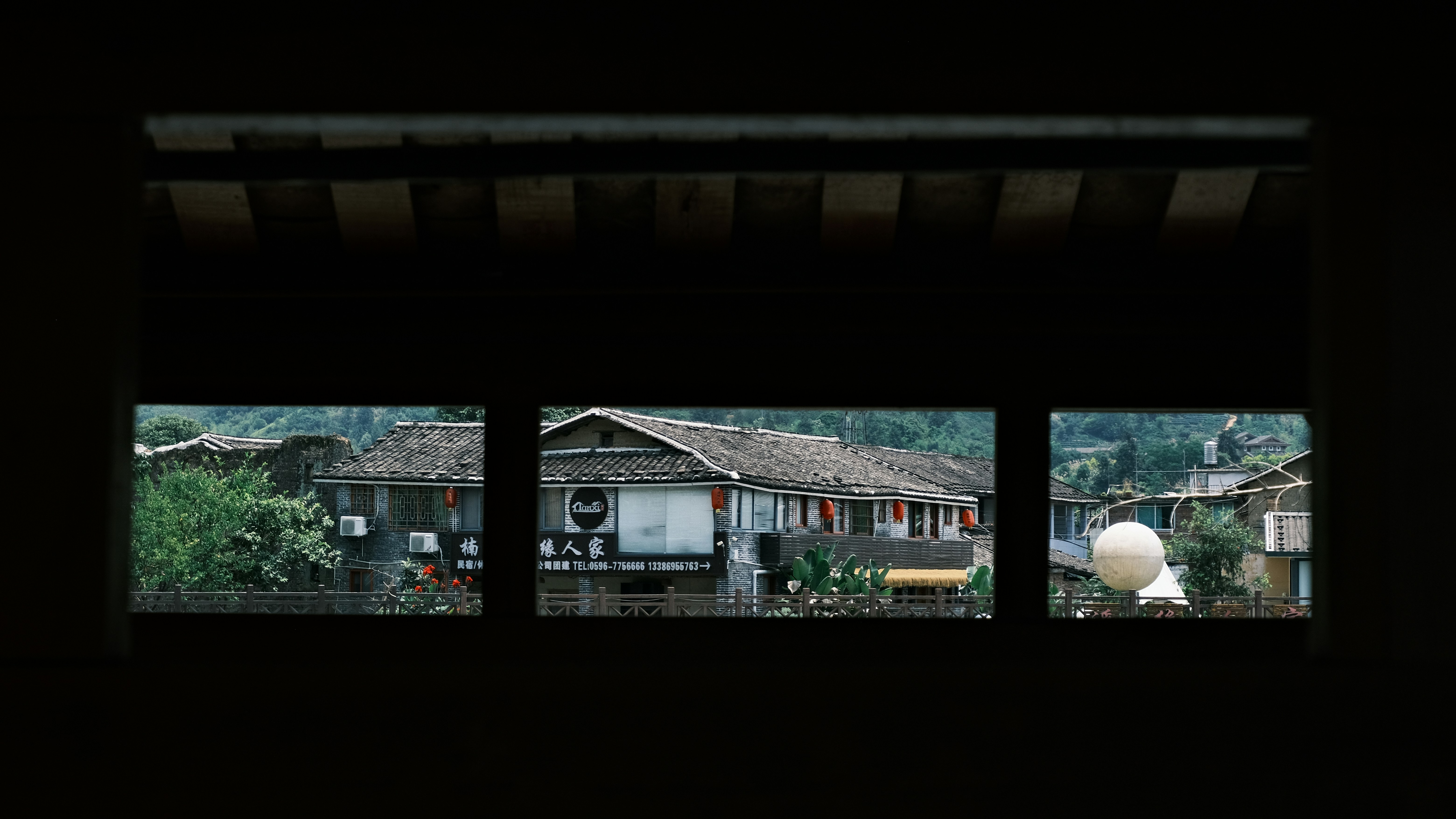 View of old village houses through a dark window.