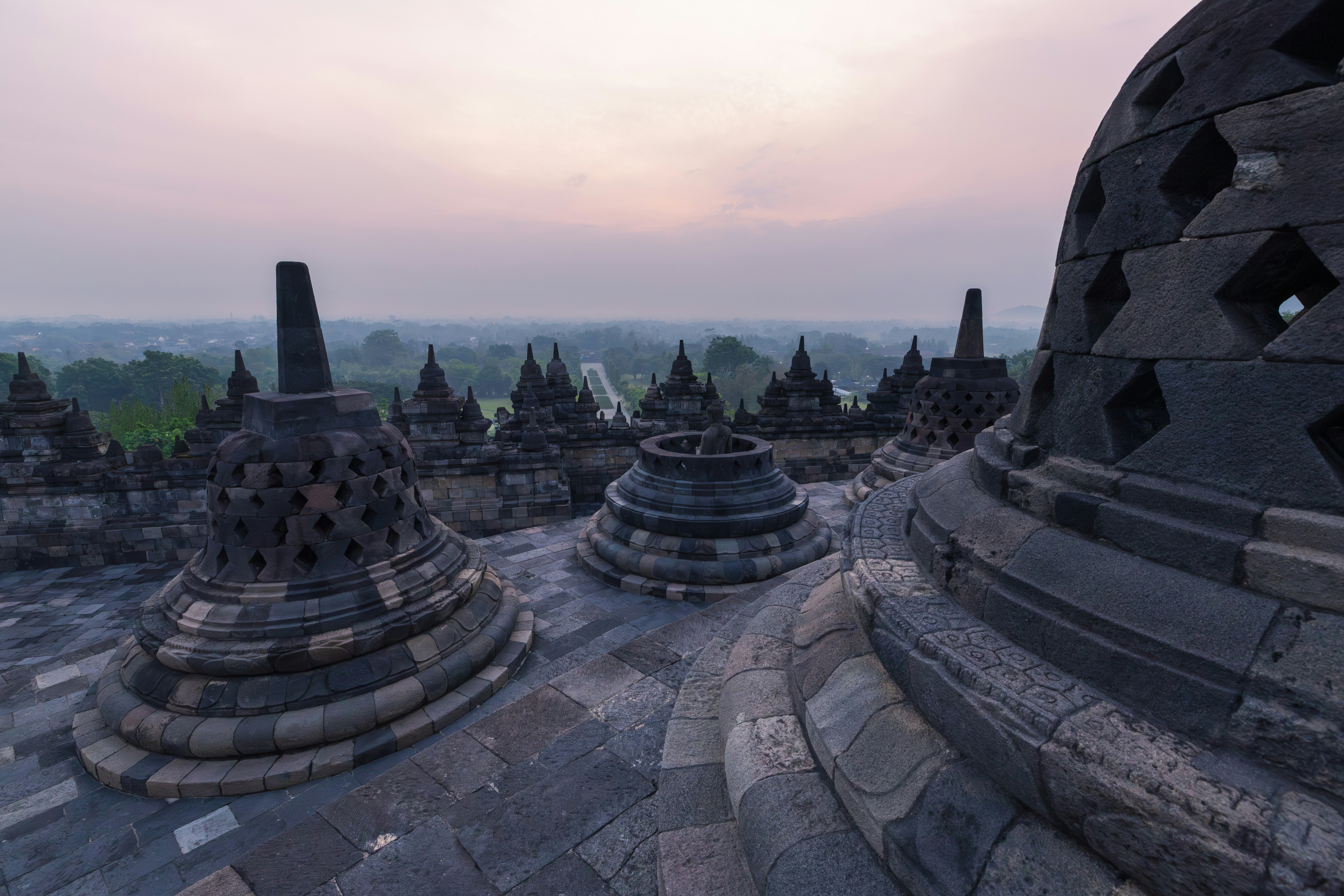 Ancient borobudur temple complex with numerous stone stupas at dawn