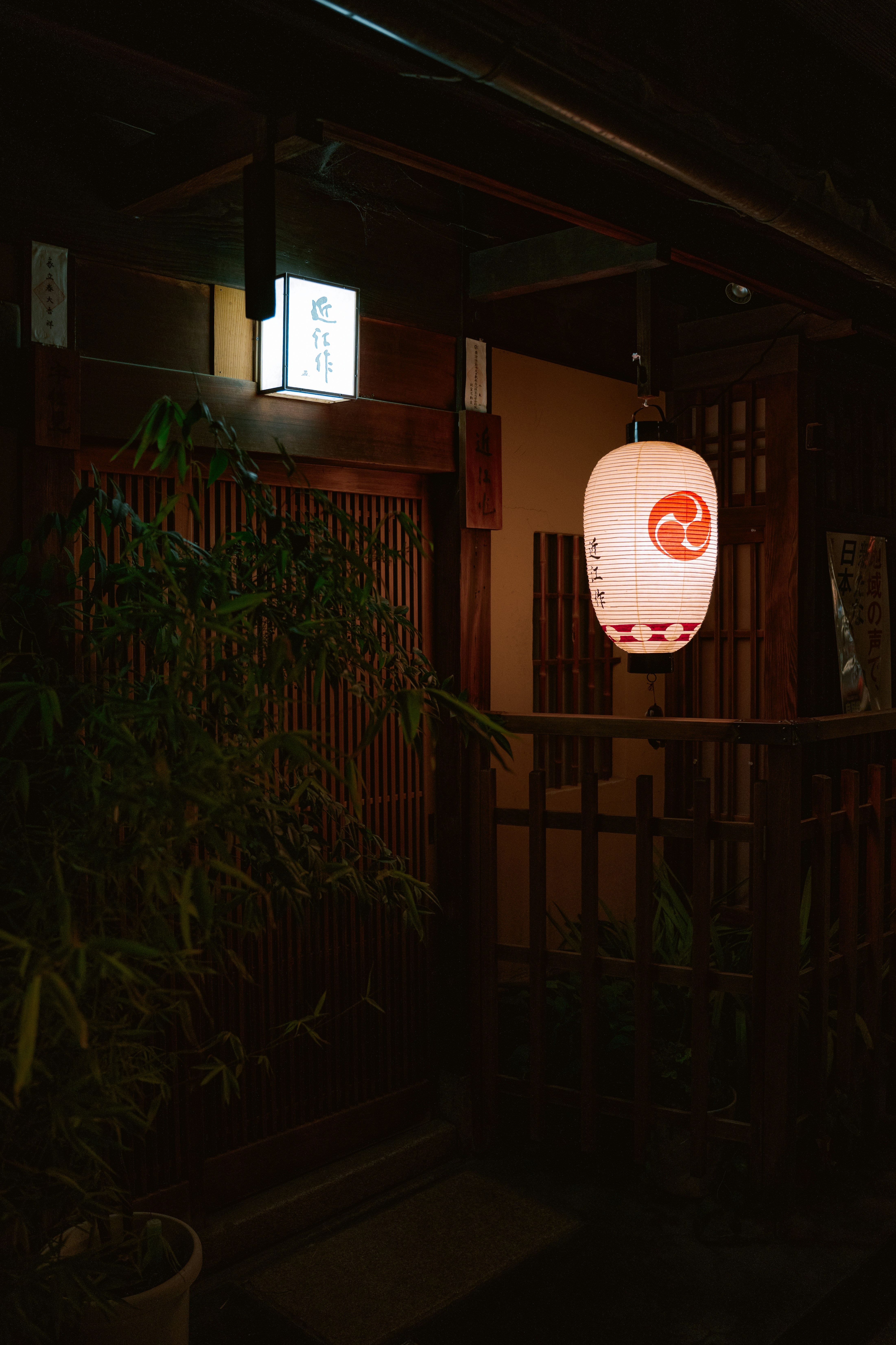 Glowing japanese lantern outside a traditional building at night.