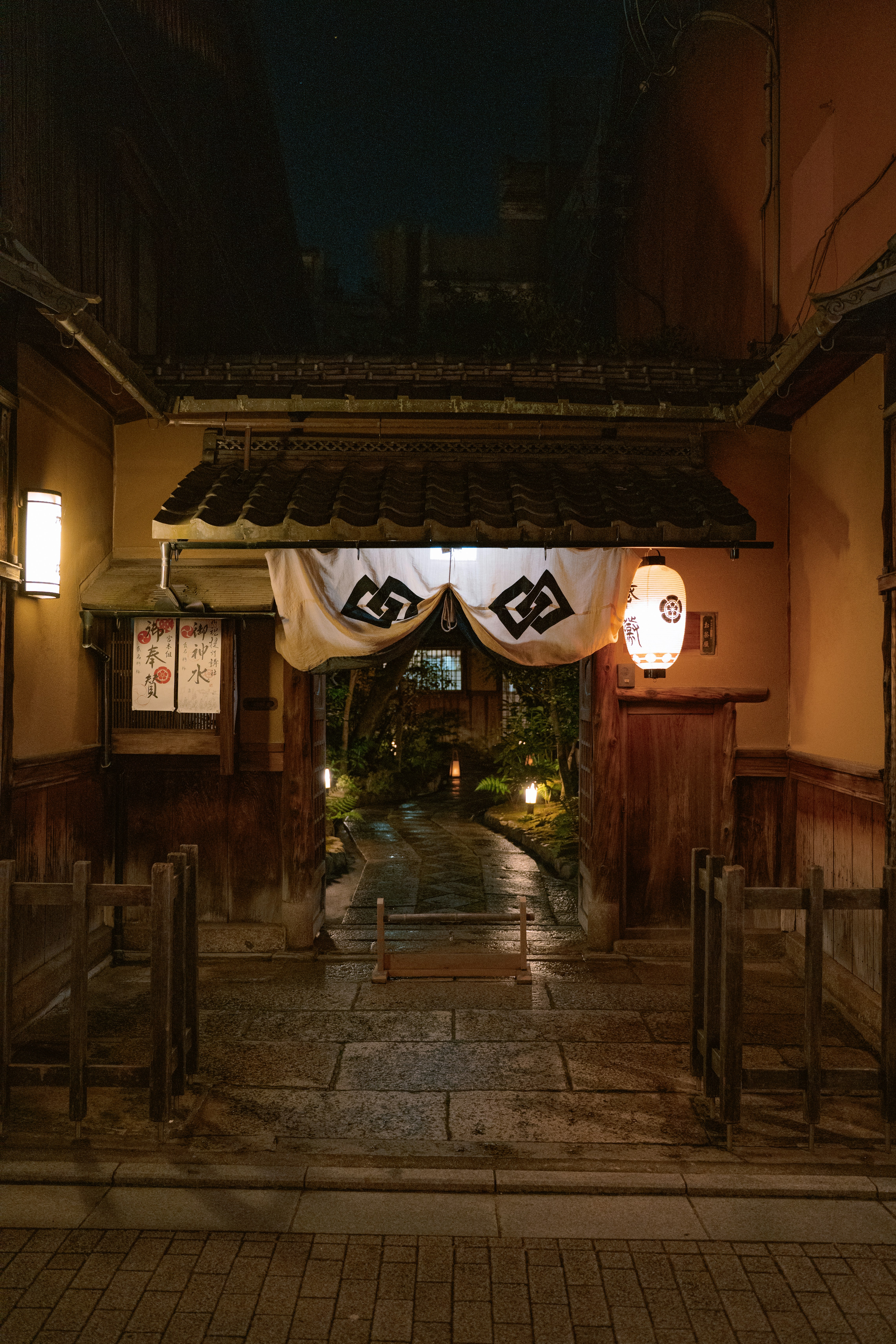 Traditional japanese entrance with noren and lanterns at night.