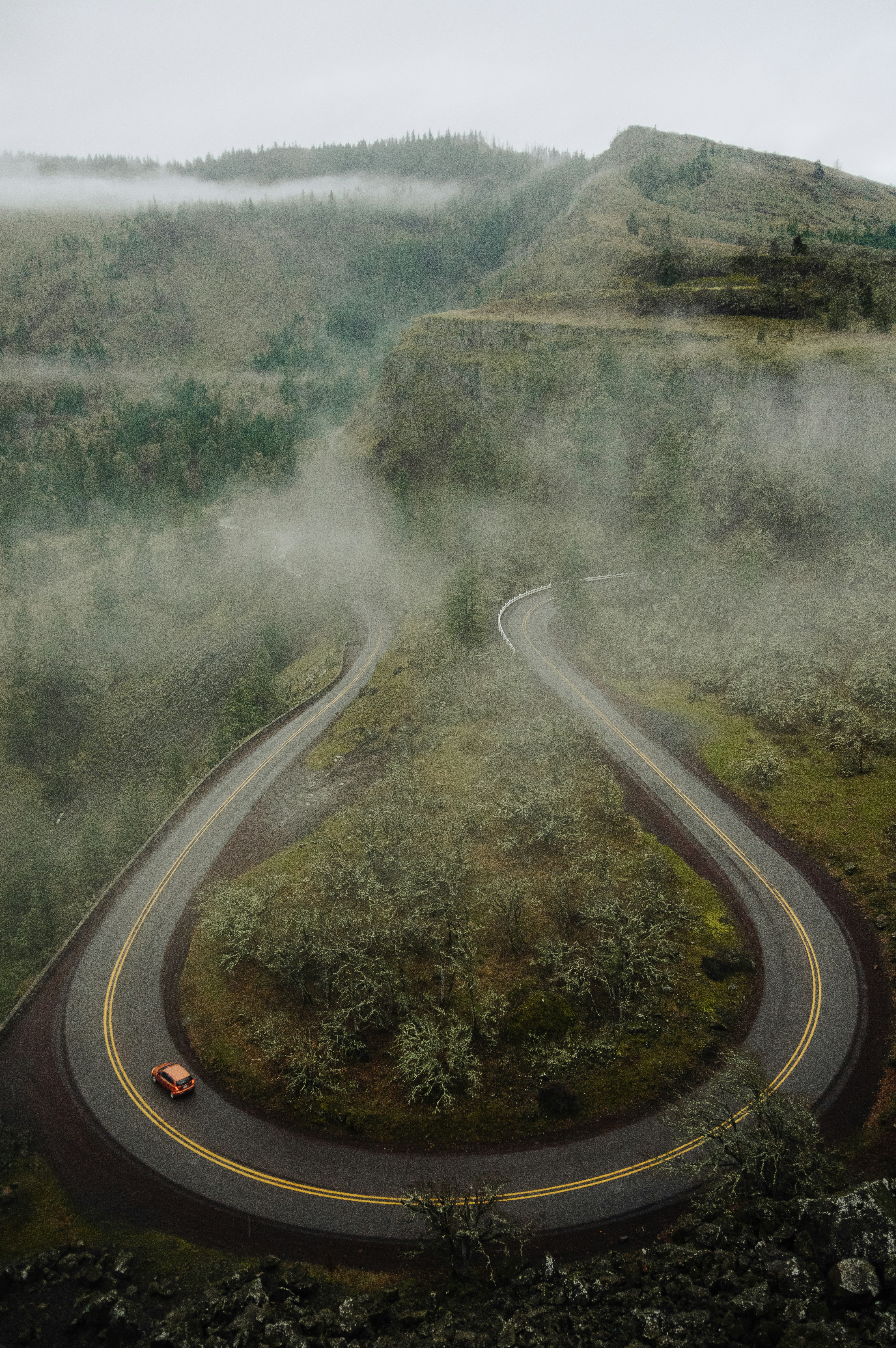 Car on a winding road through misty mountains