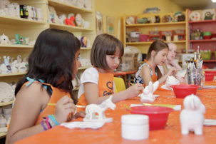 Young girls painting ceramic figures at an art studio.