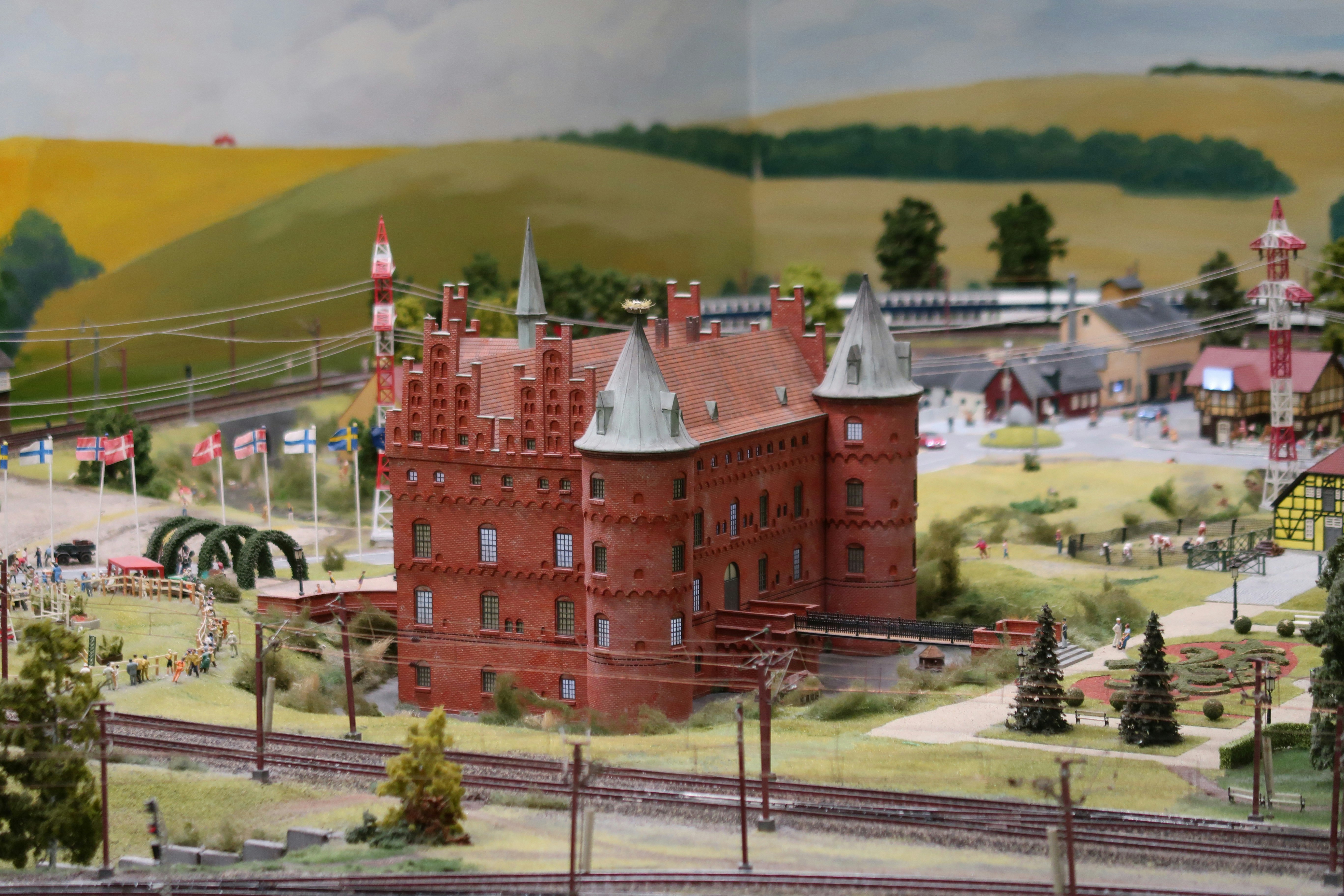 Maqueta en miniatura de un castillo de ladrillo rojo con vías de tren.