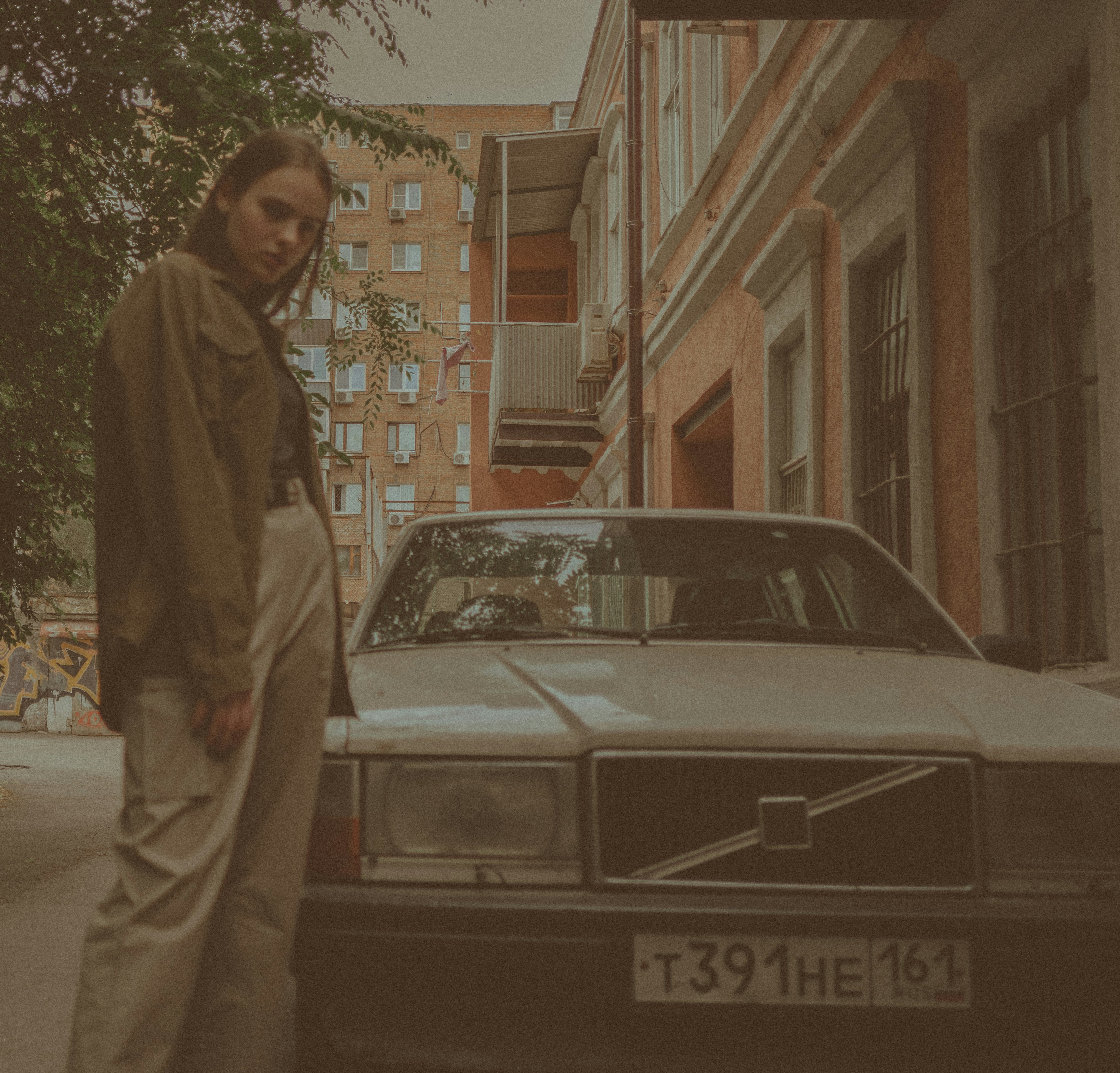 A woman stands by a vintage white car.
