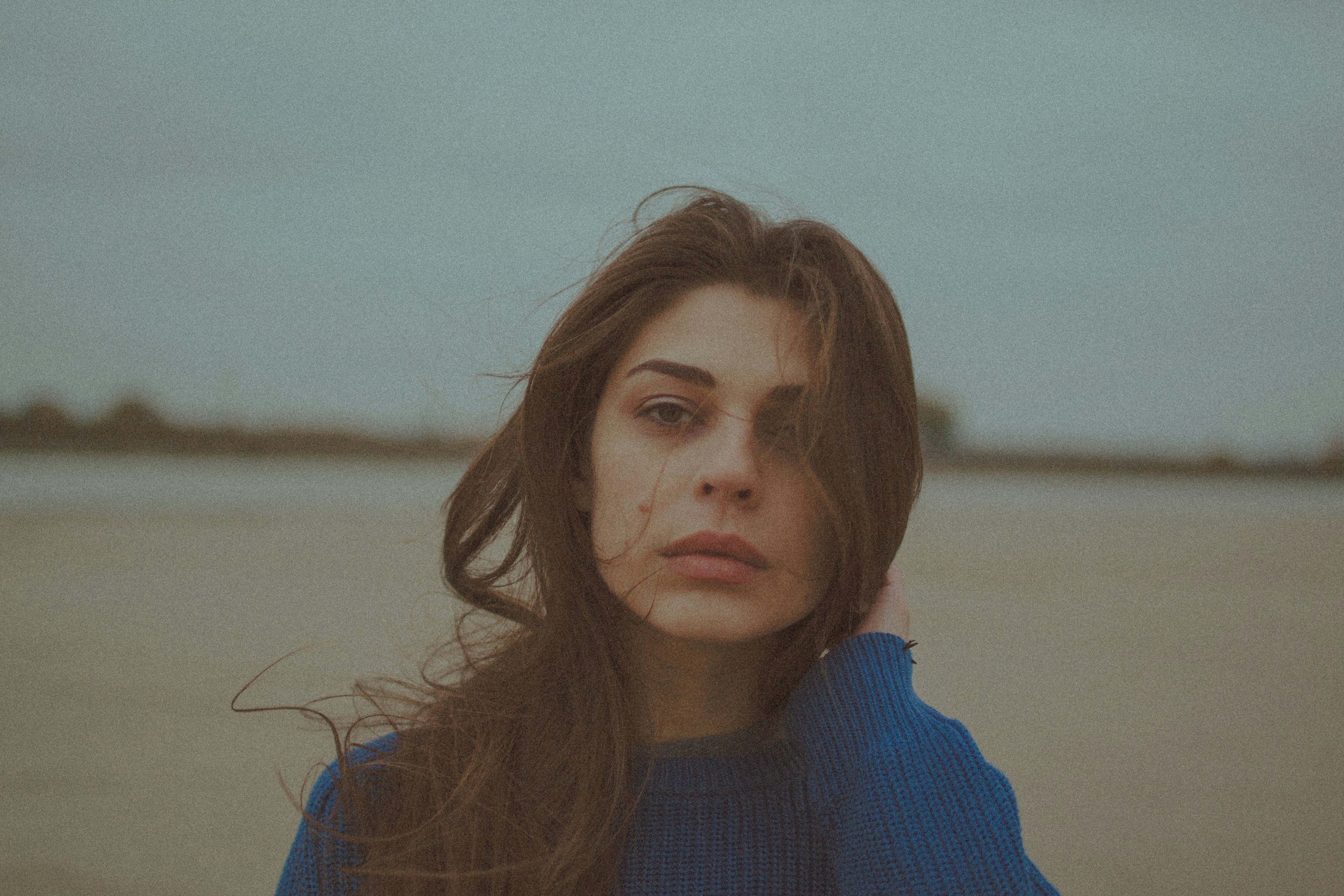 A woman with long hair and a blue sweater outdoors.