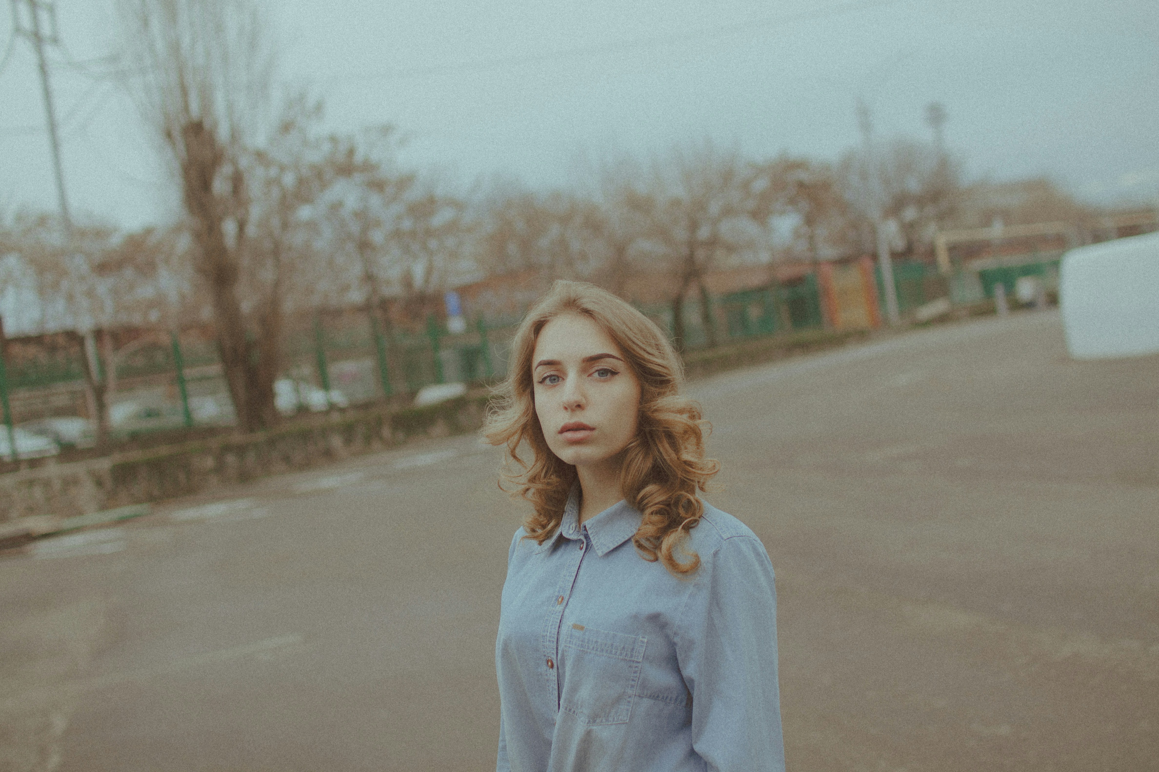 Young woman with wavy hair stands on an empty road