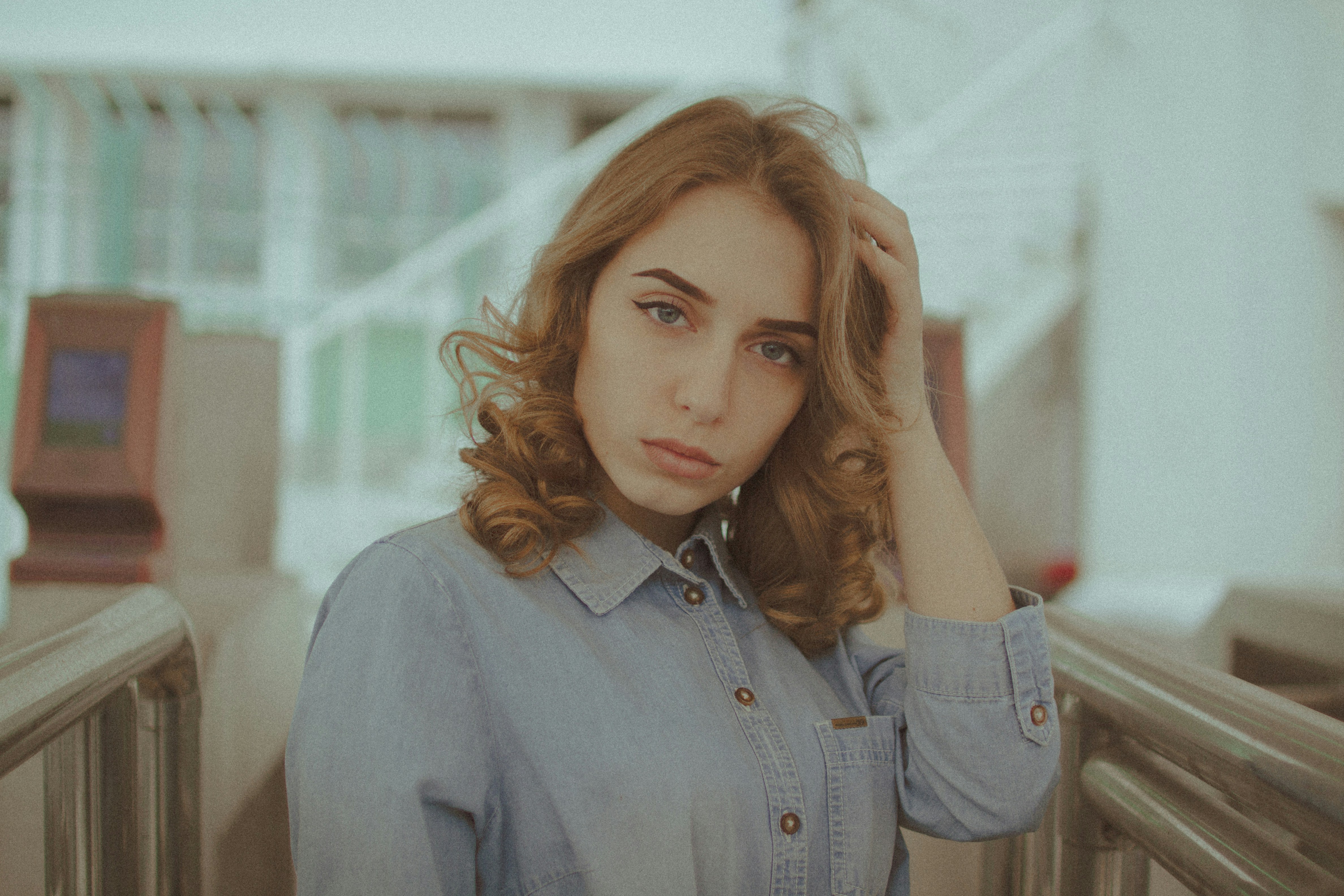 A young woman with curly hair in a denim shirt.